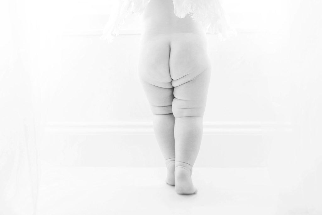 A baby's bottom has wrinkles as she stands. 