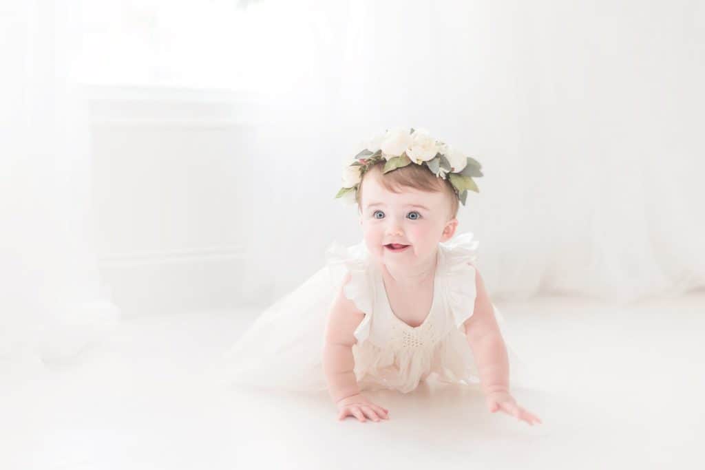 baby girl wearing a cream dress and flower crown during her First Birthday Photoshoot