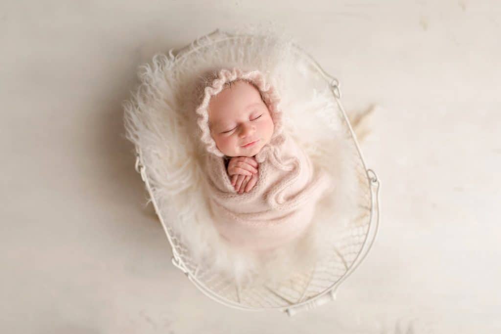 A tiny newborn sleeps in a basket. 