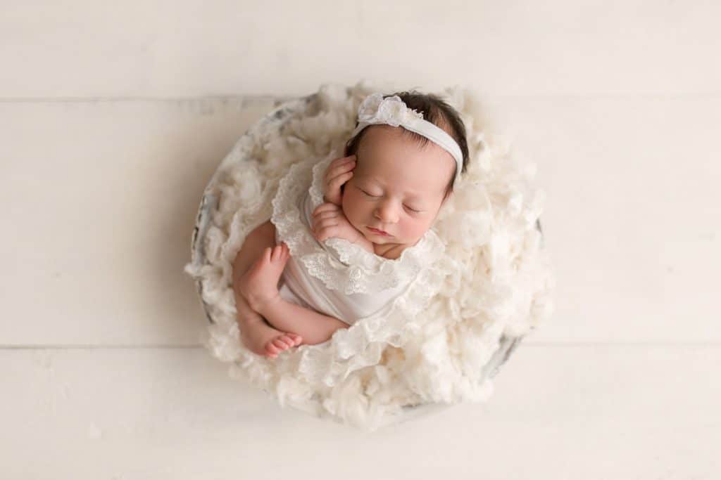 A Jupiter Newborn Photographer captures a baby sleeping in a basket. 
