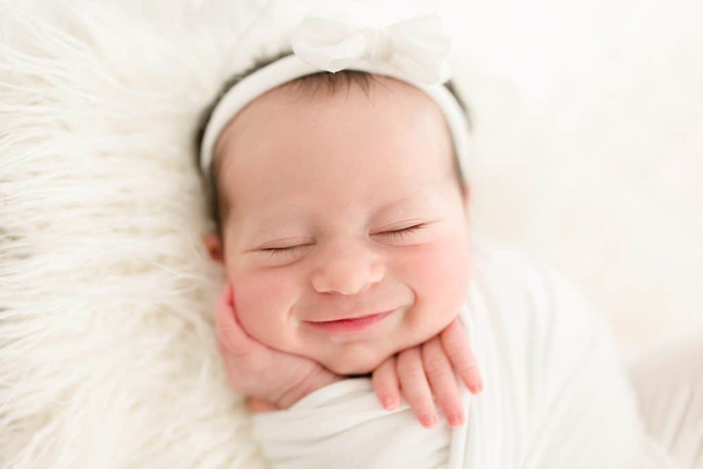 A newborn baby smiles in her sleep. 