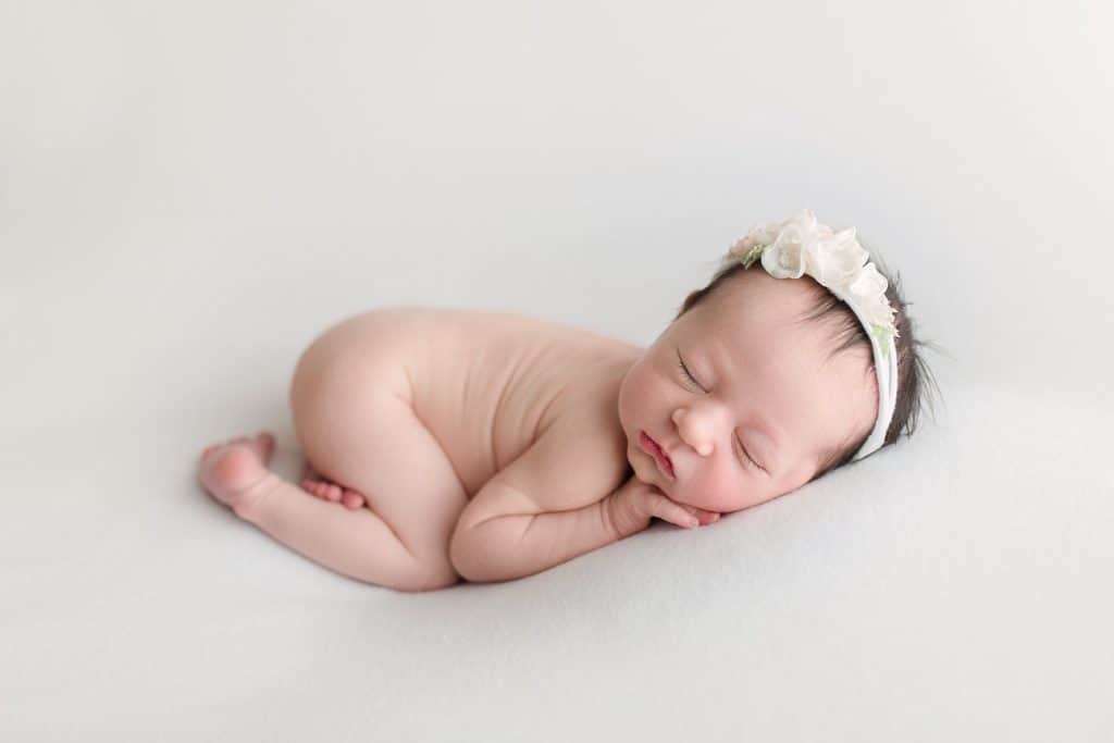 A newborn baby sleeps while naked. 