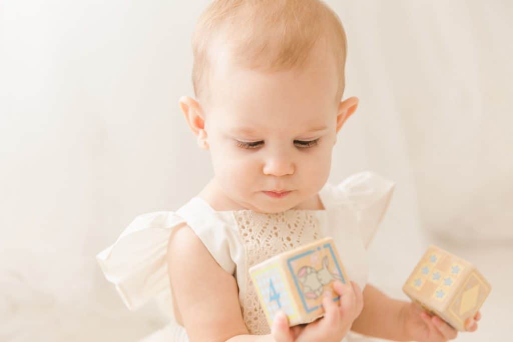 A baby girl plays with wooden blocks.
