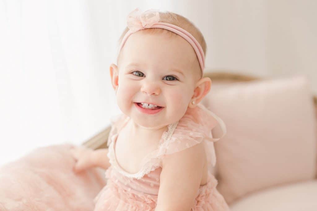 A young baby smiles as she tilts her head up.