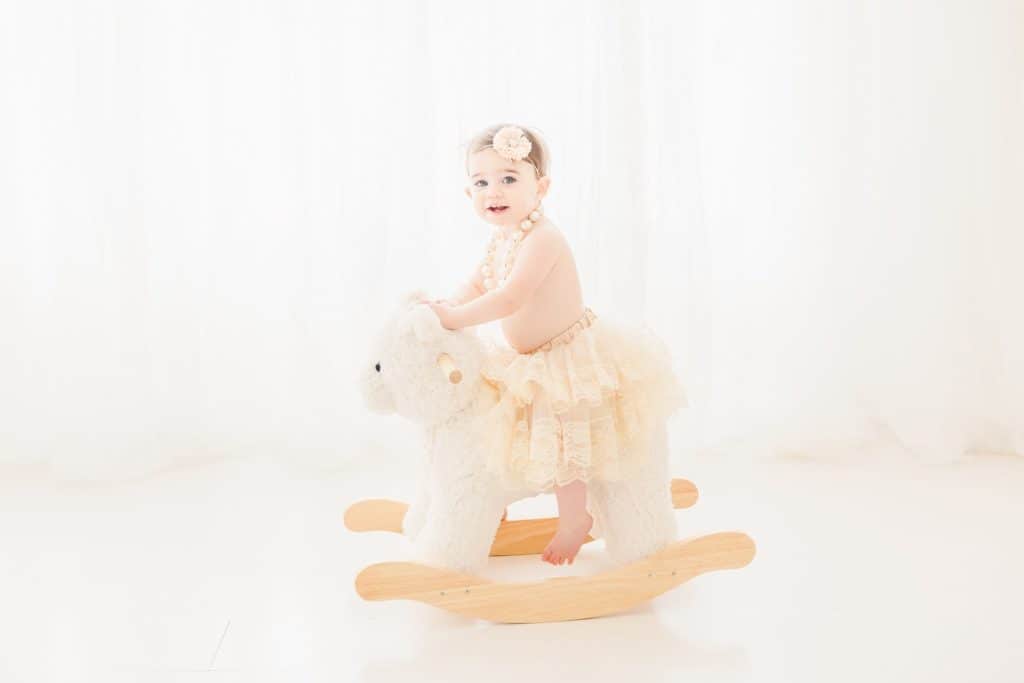A baby sits on a rocking horse. 