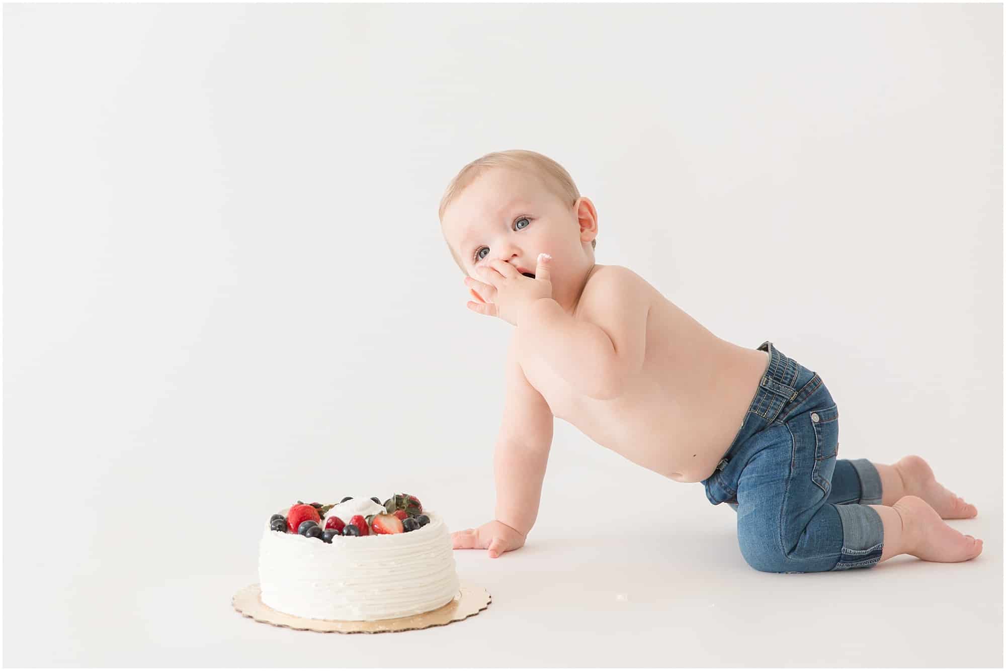 Baby Photographer photographing a one year old smashing his white birthday cake covered in fresh fruit in Palm Beach 