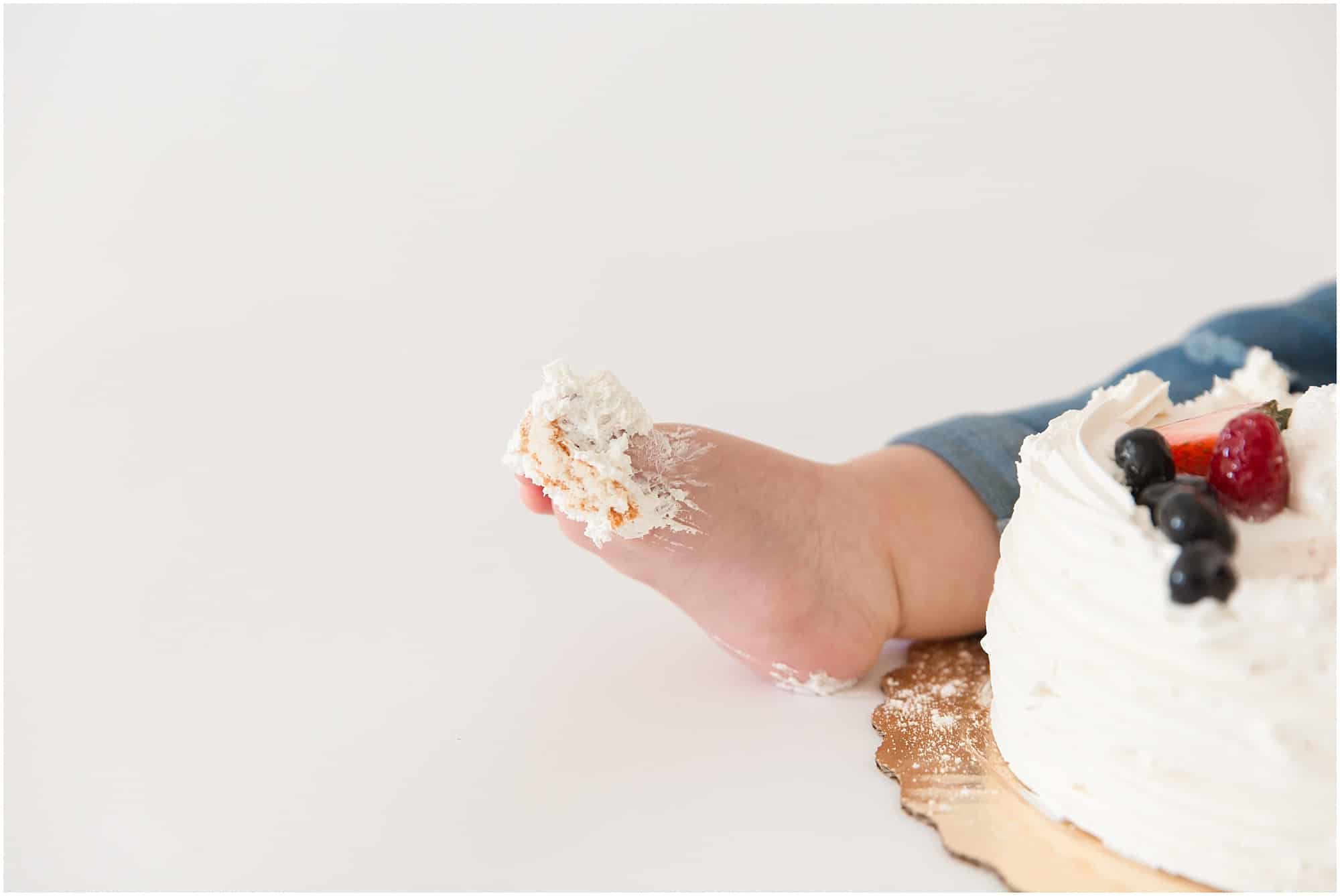 Baby Photographer photographing a one year old getting his toes covered in sticky white icing  in Palm Beach 