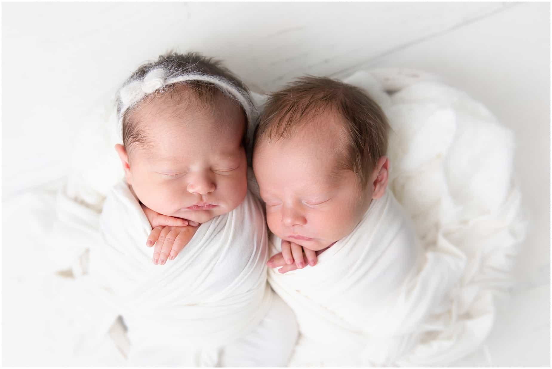 Photos of Newborn Twins swaddled in white snuggling in a heart shaped bowl in Jupiter photography studio 