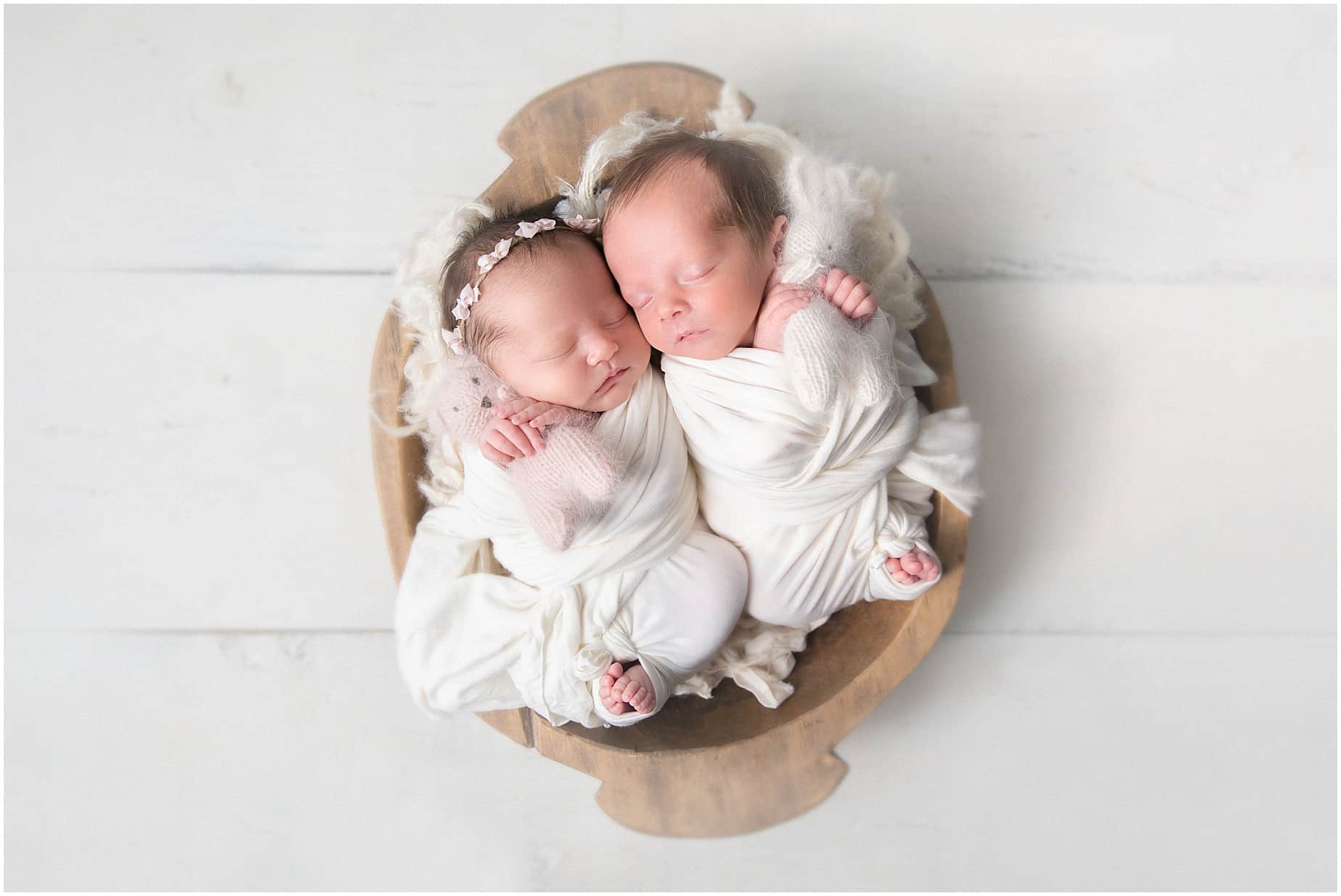 Photos of Newborn Twins swaddled in white snuggling in a bowl holding bunnies in Jupiter photography studio 