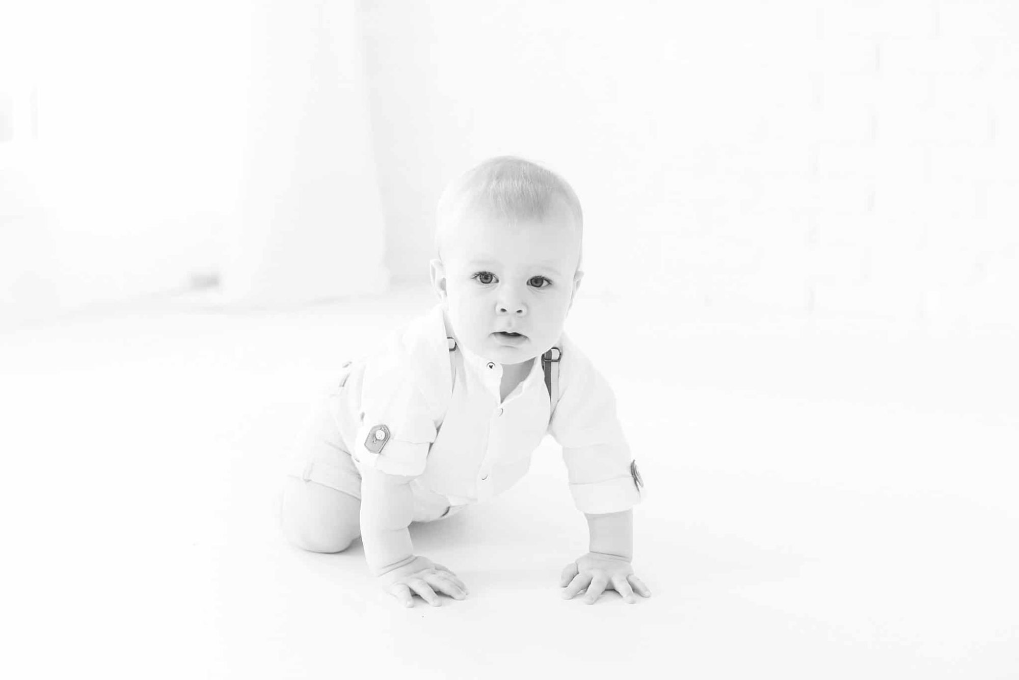 One year old baby crawling in photo studio.