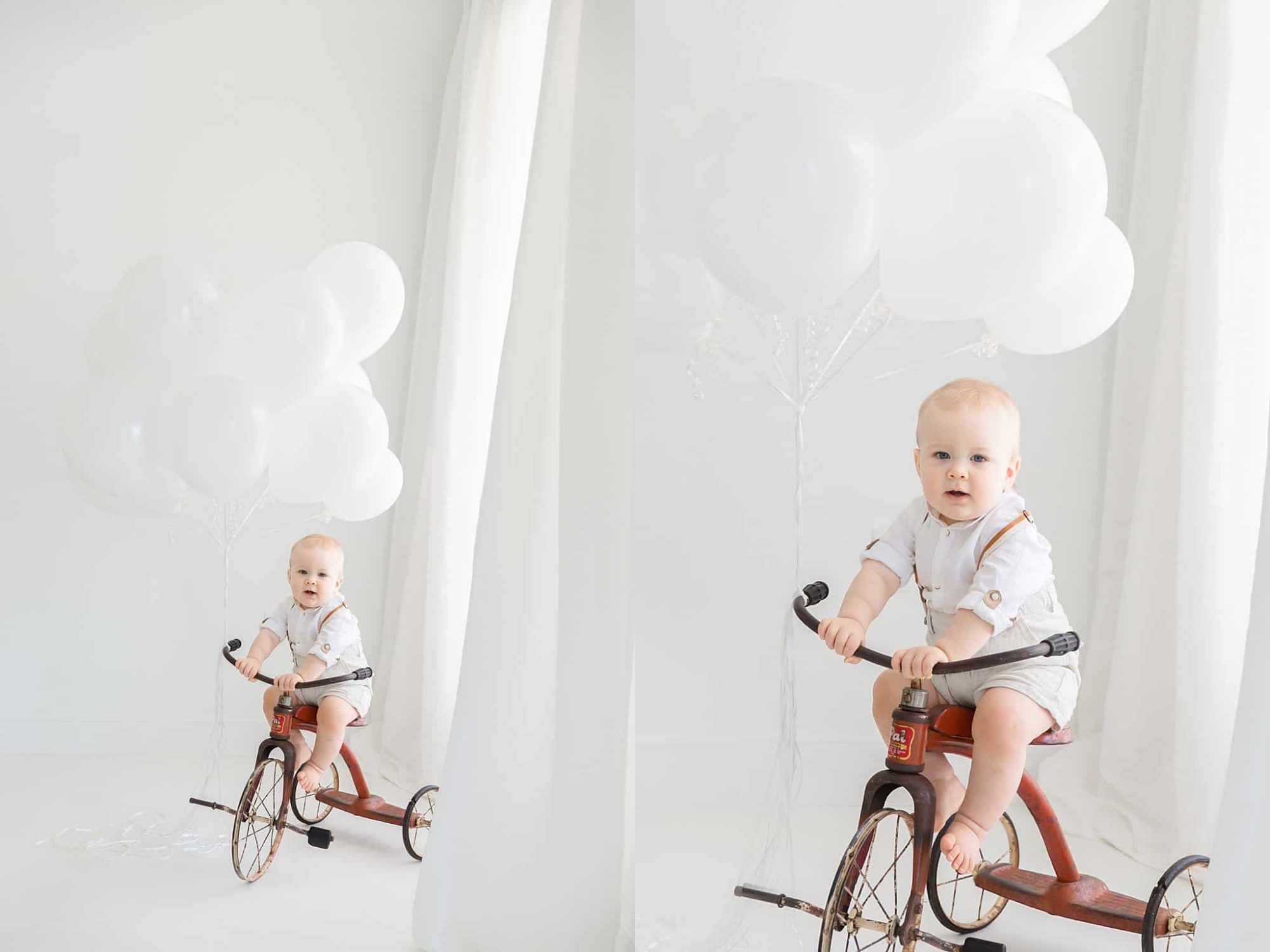 Birthday boy sitting on tricycle with white balloons tied to handle.
