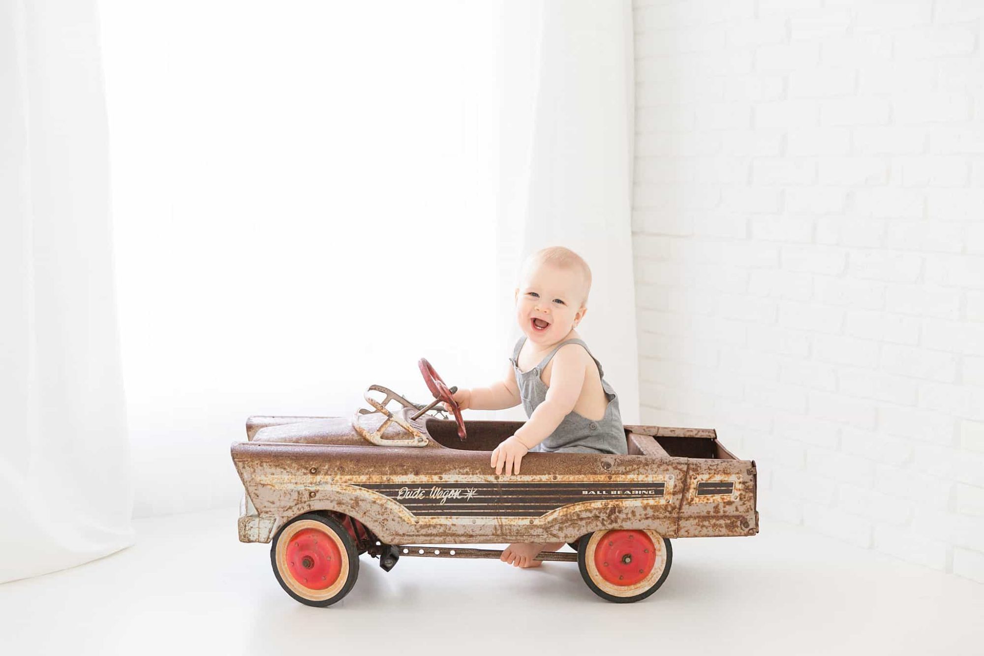 Baby boy in vintage Dude Wagon pedal car.