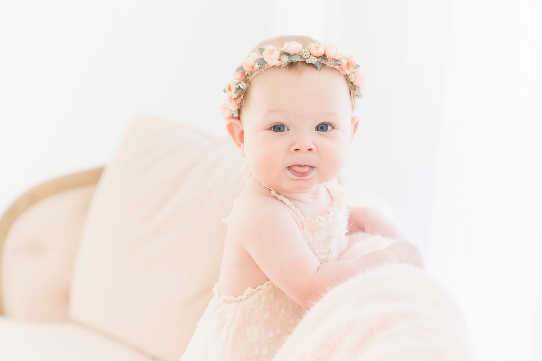 Photos of a baby girl standing a on pink couch with flower halo on her head in Jupiter Fl