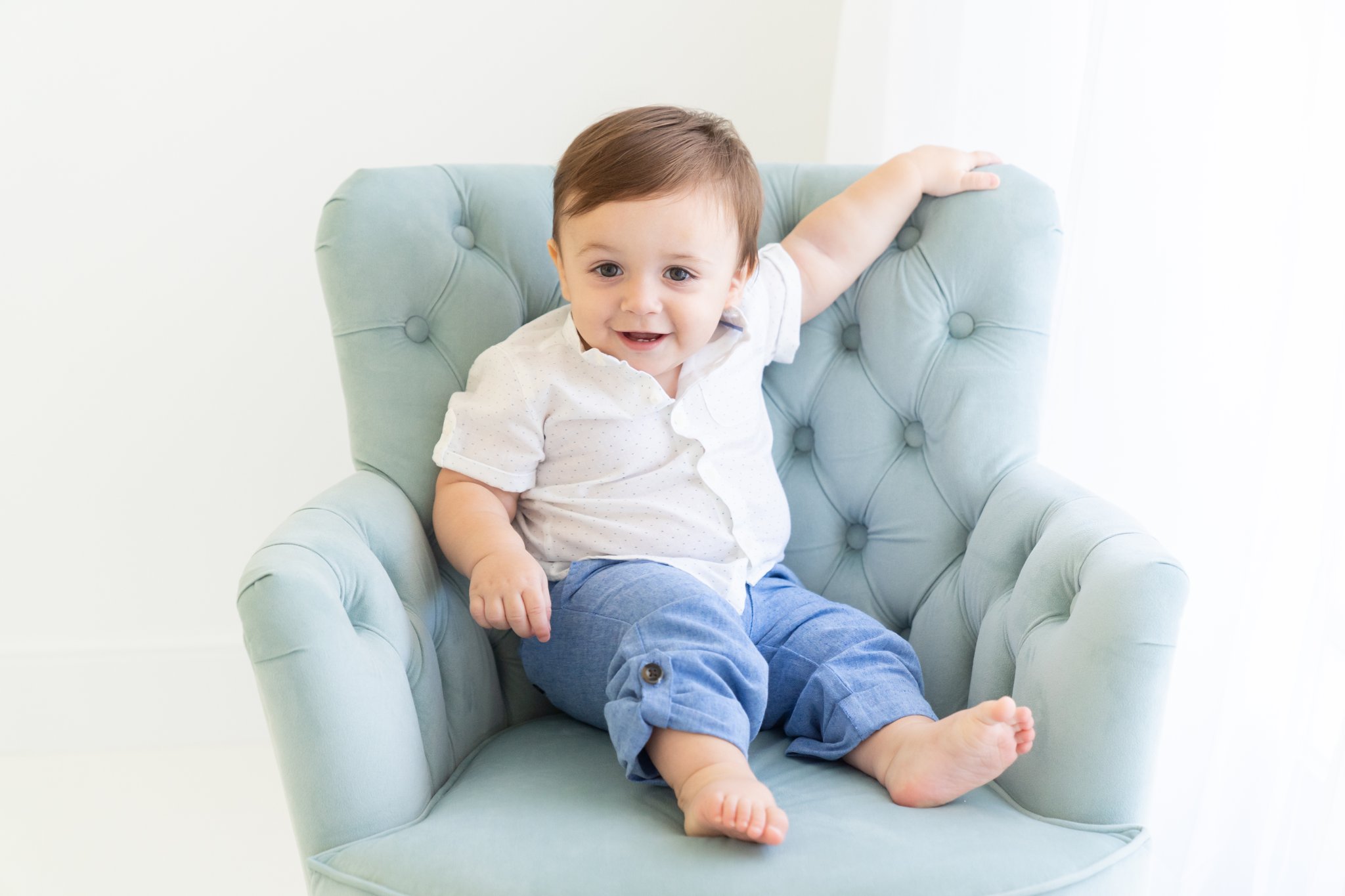 Baby boy sitting in turquoise chair.
