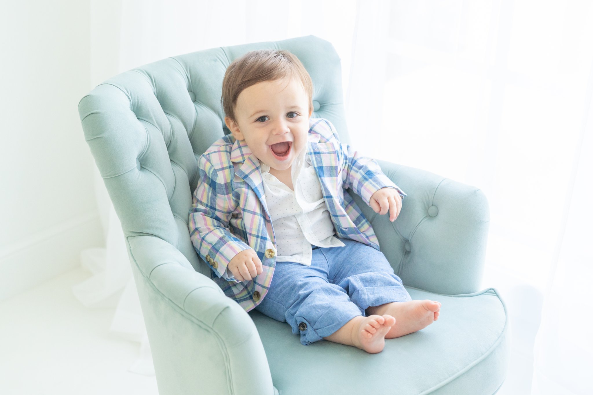Baby boy sitting in turquoise chair.
