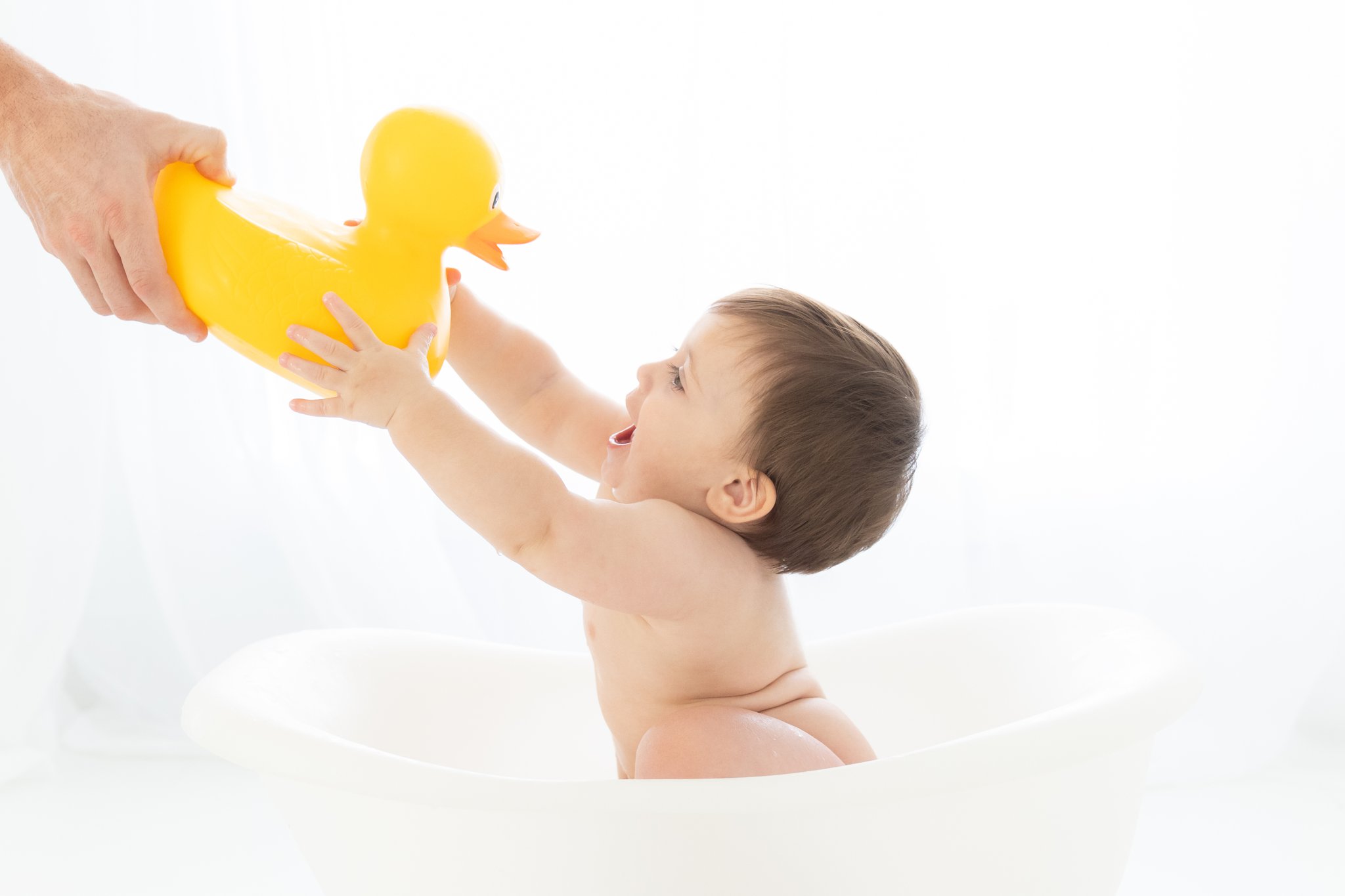 Baby boy splashing in water play tub while being photographed in Jupiter photography studio.