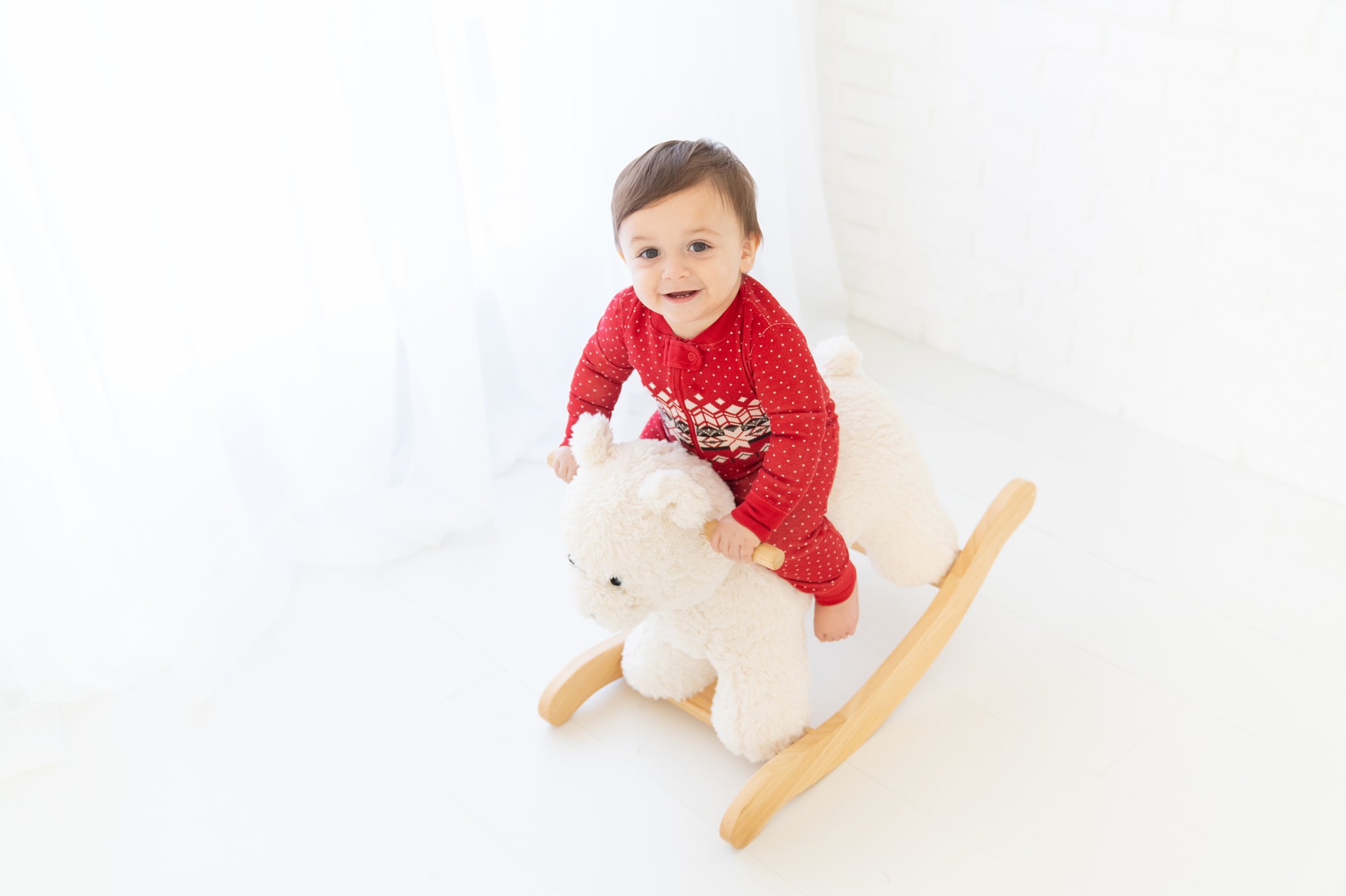 Baby boy in pajamas playing with white polar bear rocker in Jupiter Baby Photography studio