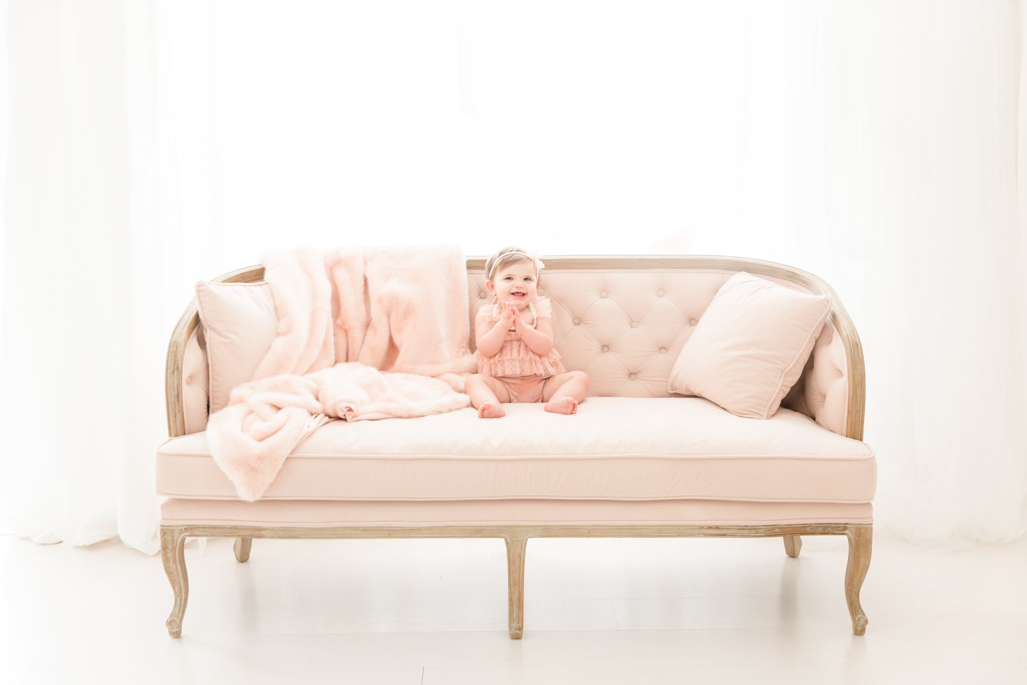 Baby on pink settee in Jupiter photography studio