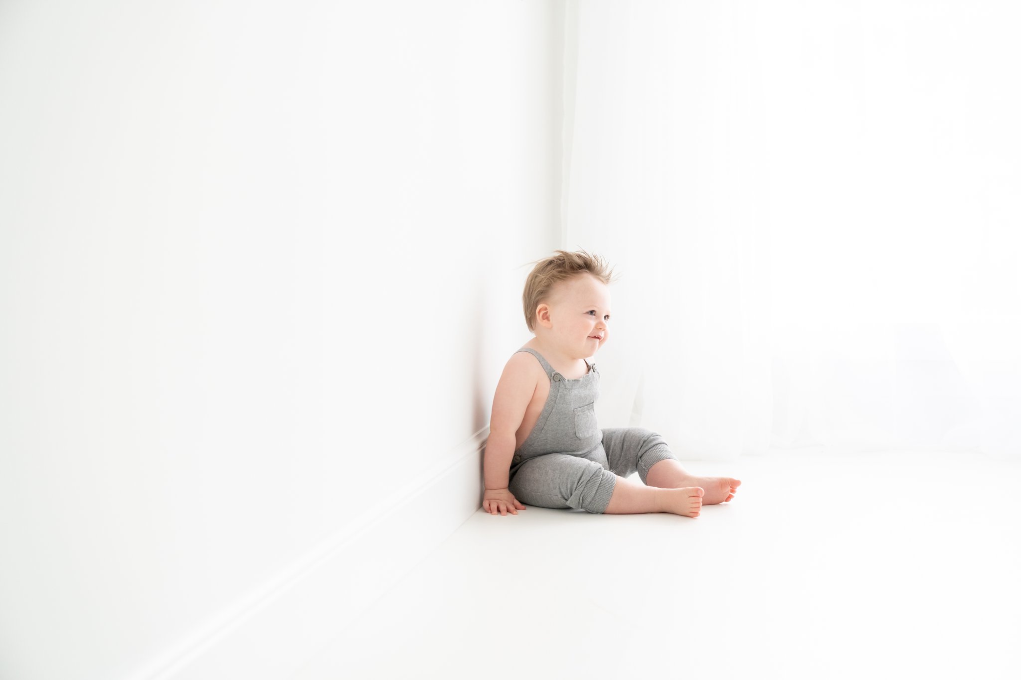 Birthday photo shoot for a one year old baby in a  grey romper.