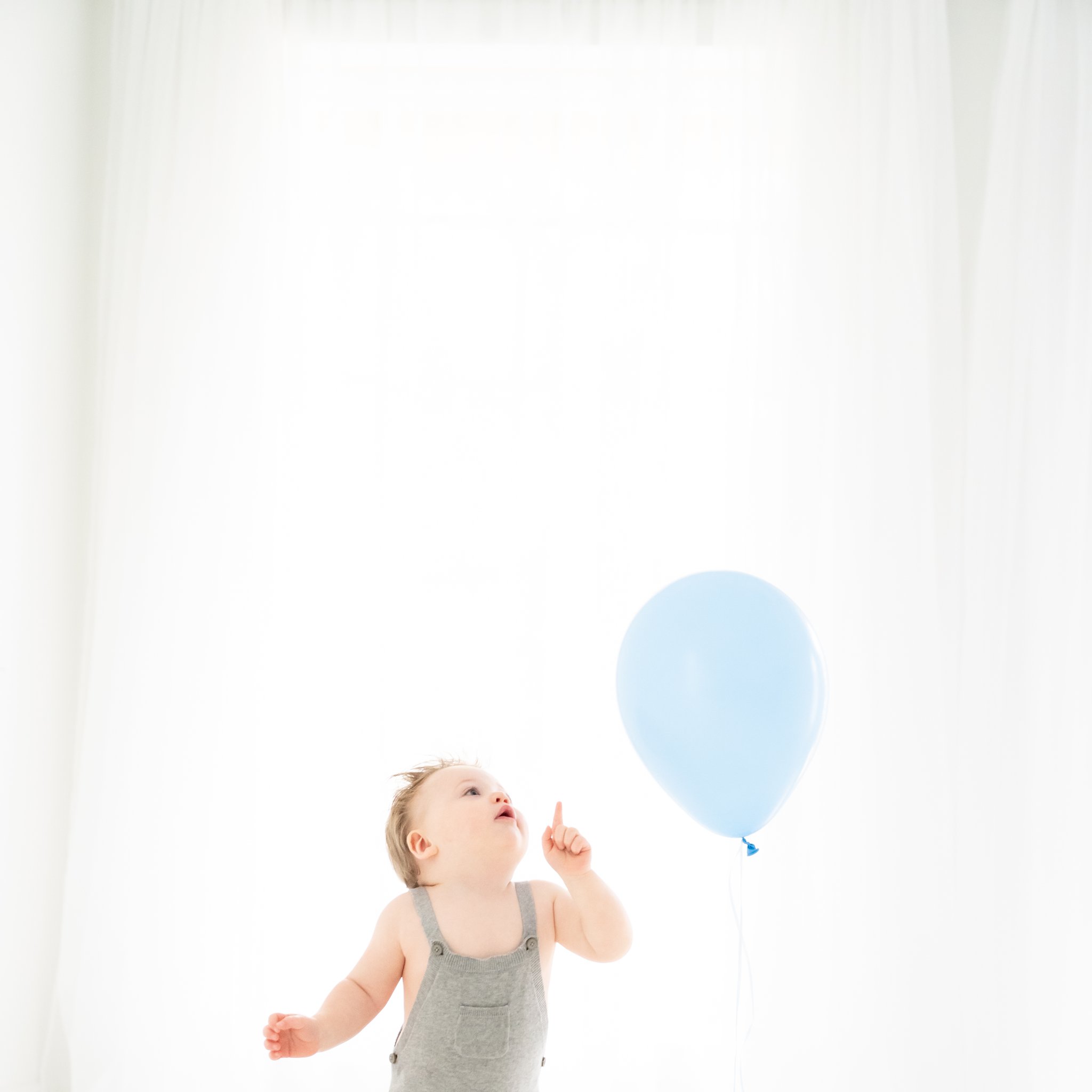 Birthday photo shoot for a one year old baby in a  grey romper.