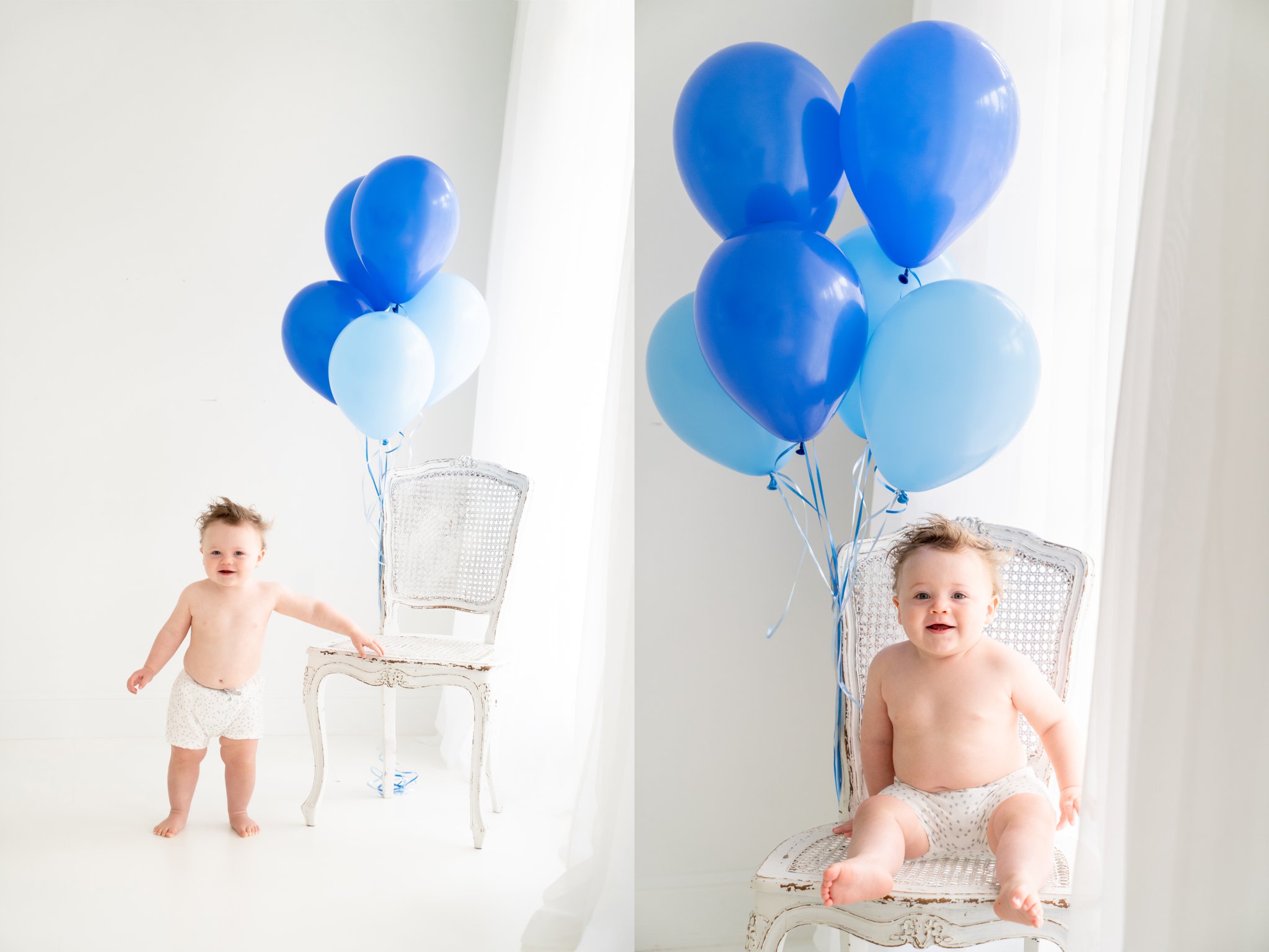 Birthday baby with blue balloons being photographed by bright window in a white chair.