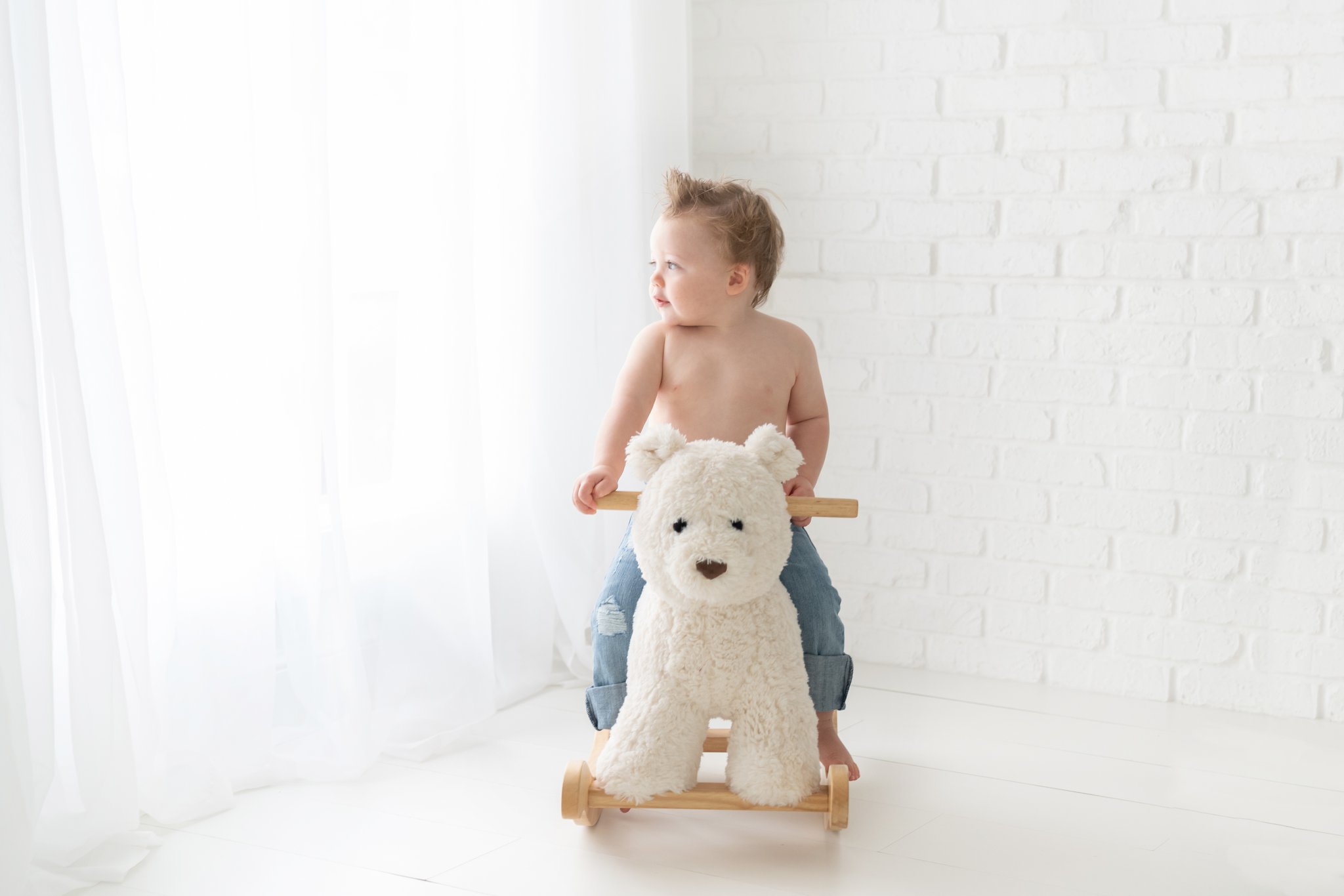 Birthday boy being photographed with Pottery Barn rocking bear in Jupiter Fl baby photography studio.