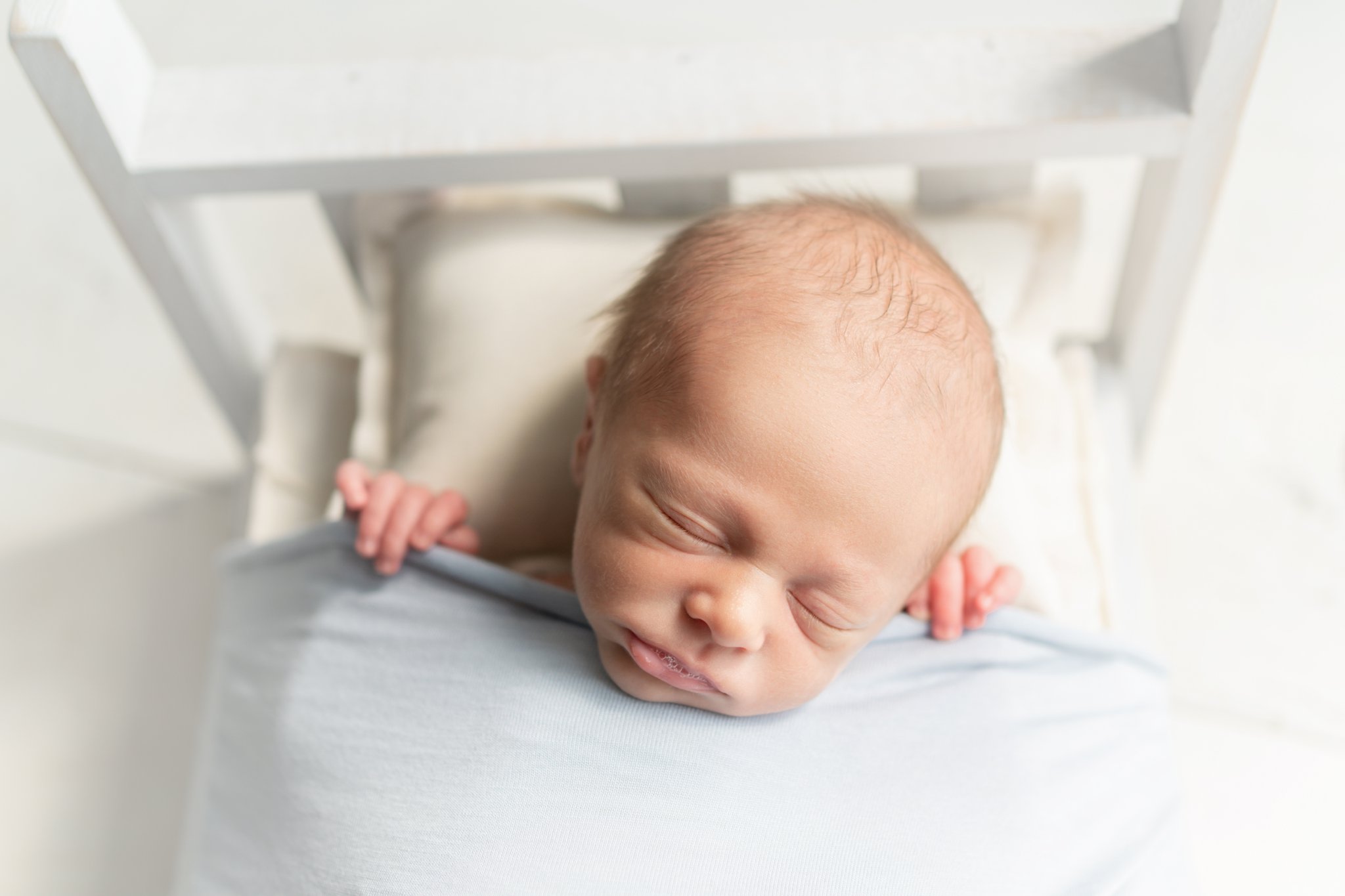 Newborn baby in tucked into little wooden prop bed being photographed in south florida photo studio.