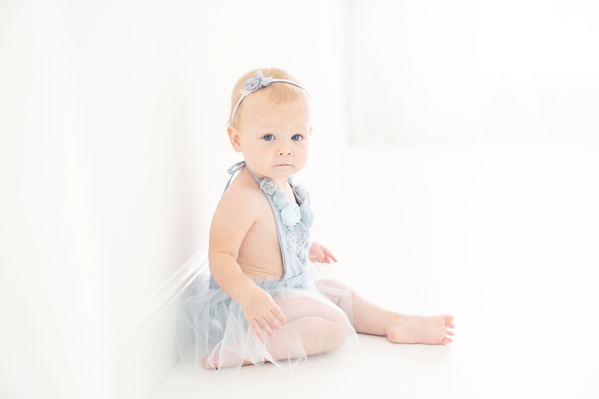 Baby girl being photographed in a south florida photography studio in blue handmade dress.