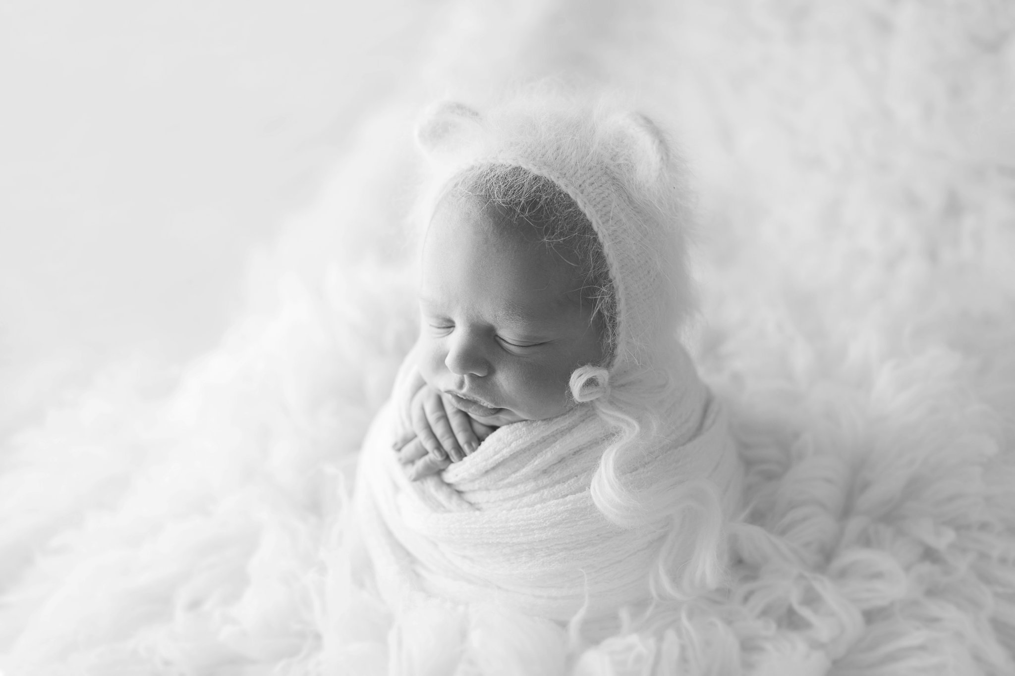 10 day old newborn posing on a white backdrop with a little bear hat in West Palm Beach Photography studio