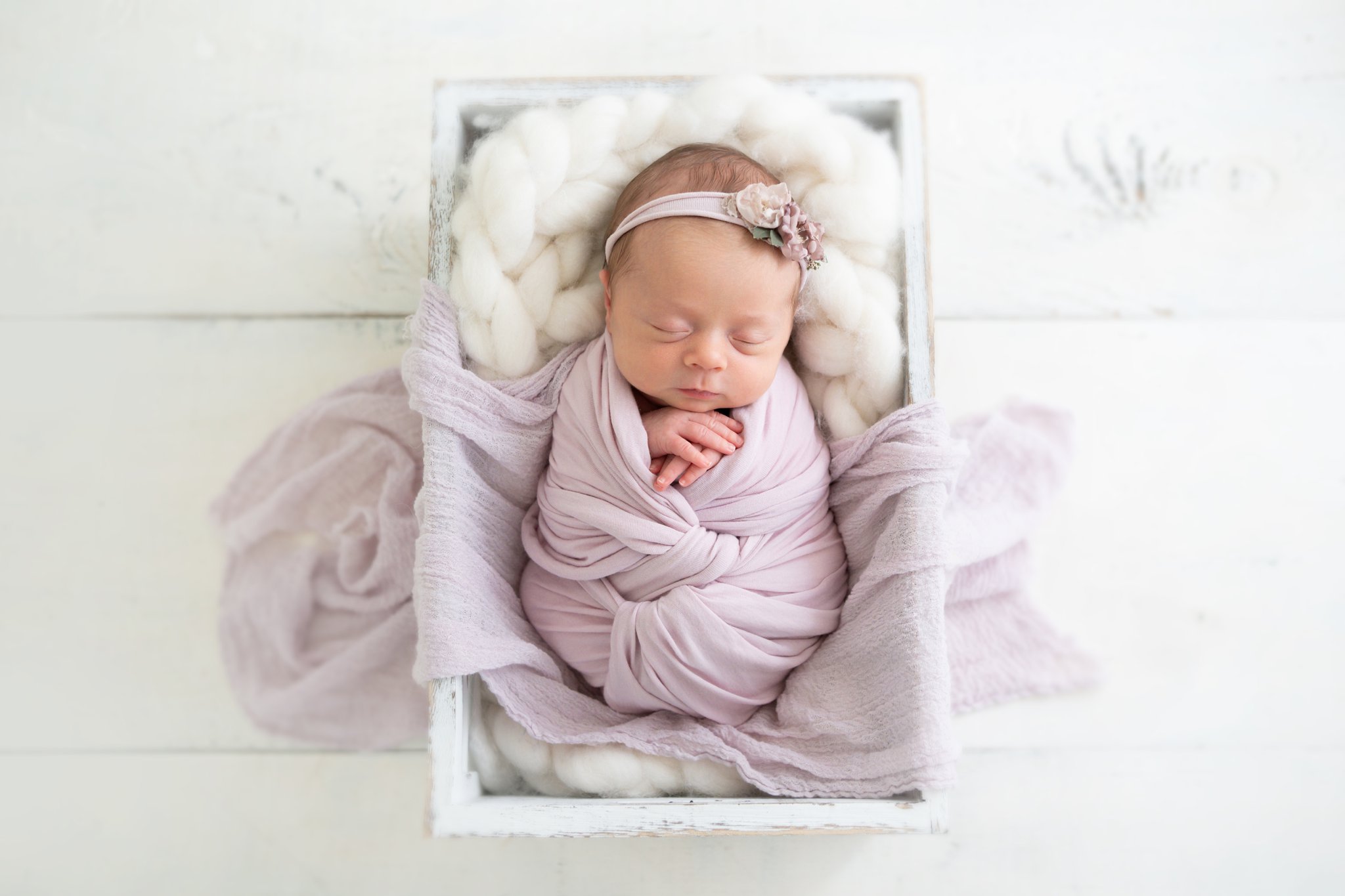 newborn baby wrapped in lavendar laying in crate being photographed in jupiter photography studio
