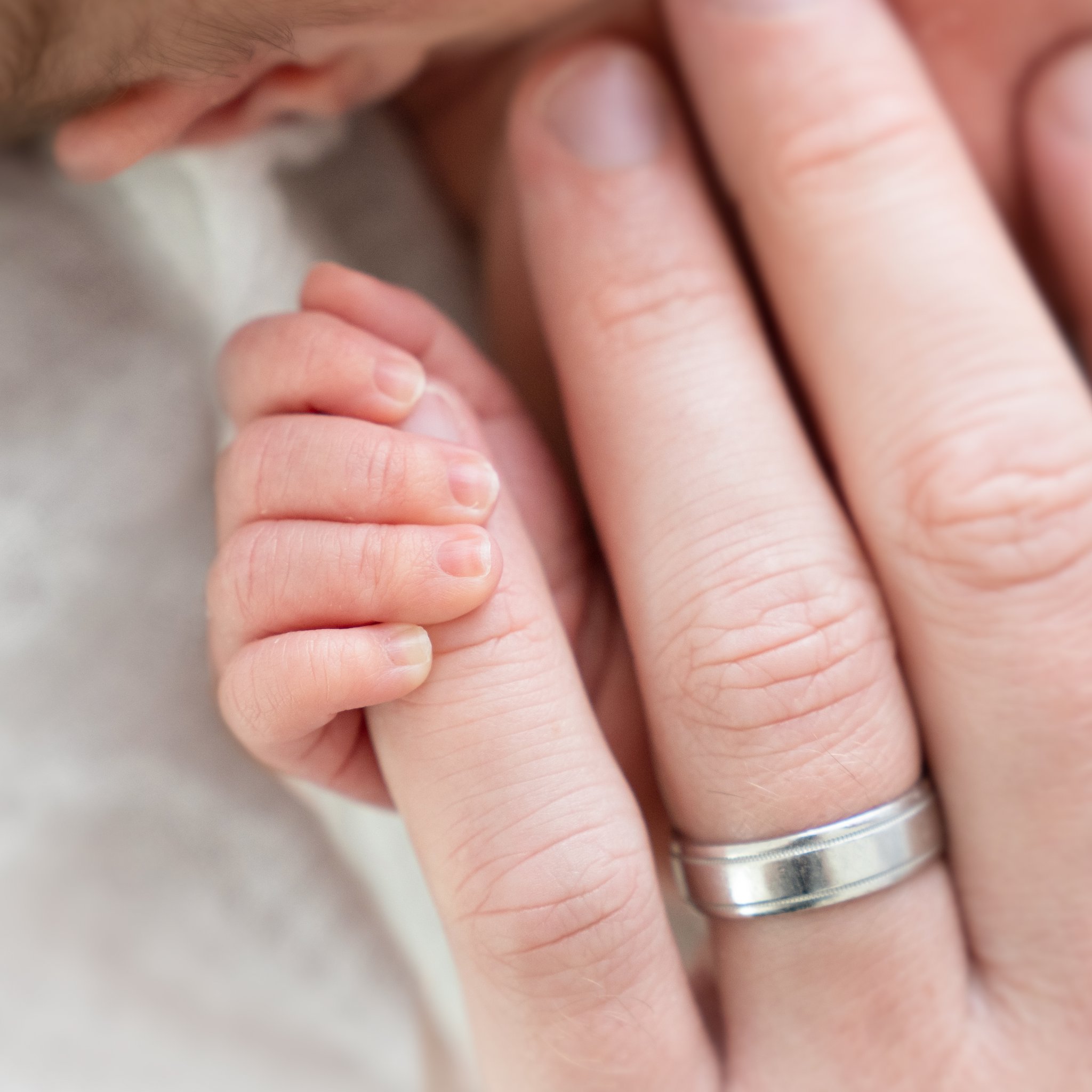 baby holding dad's pinky finger close up being at a Family Newborn Session