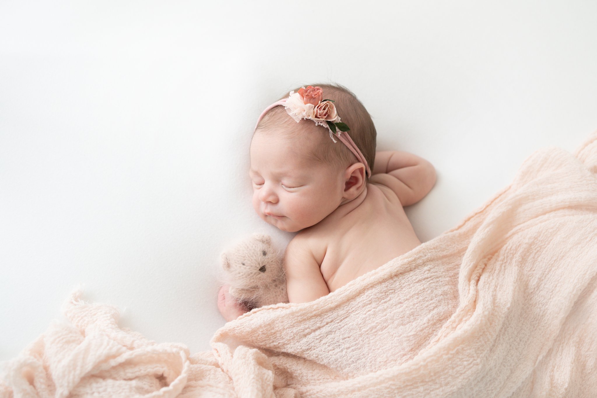 newborn baby baby being photographed in Jupiter baby photo studio laying down wrapped in pink