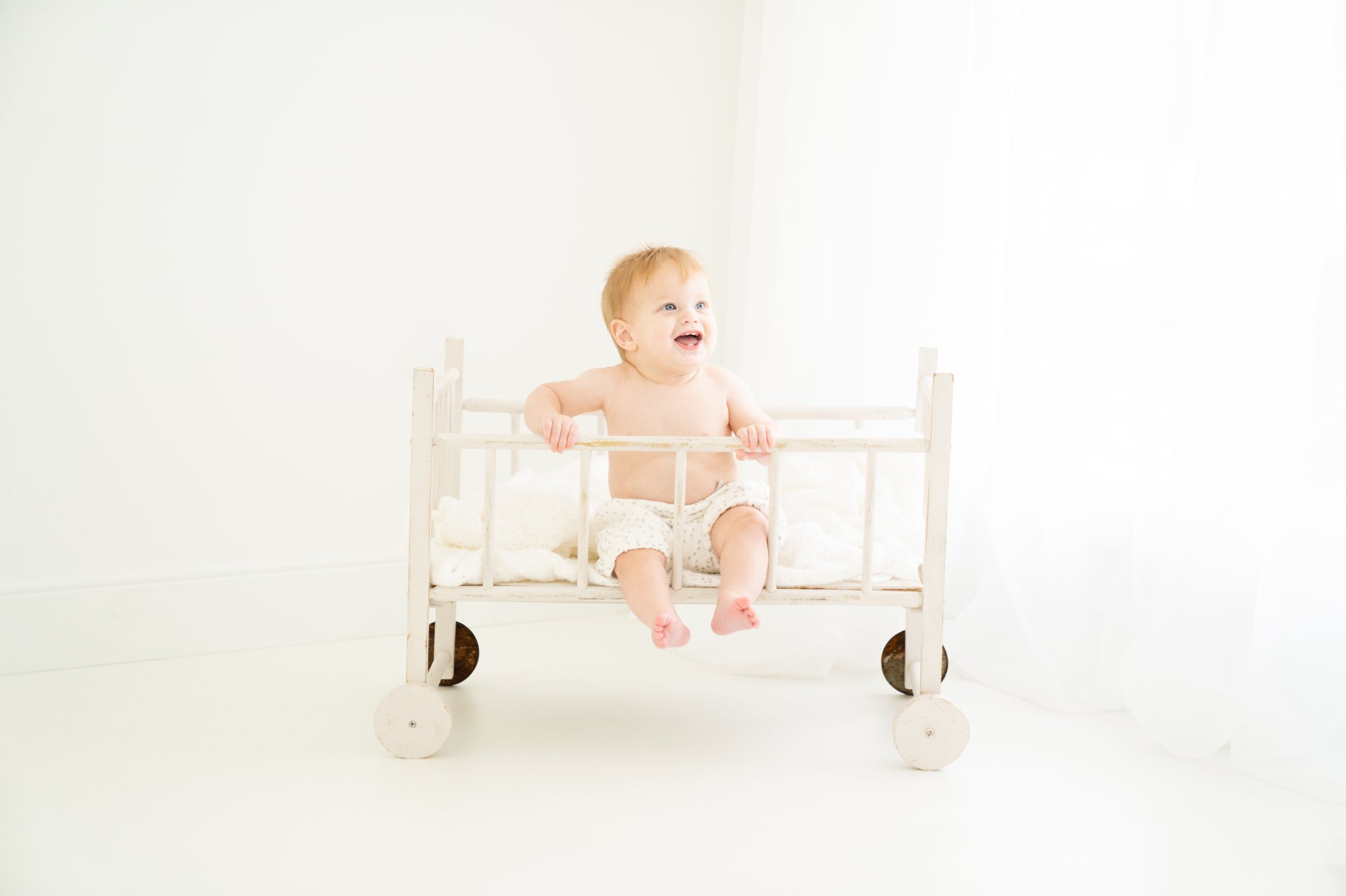 6 month old baby being photographed in vintage crib in Jupiter Fl studio