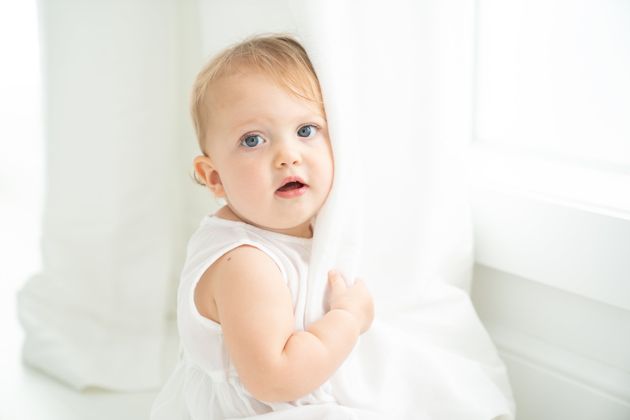 12 month old baby girl in white having her pictures taken in jupiter photography sttudio