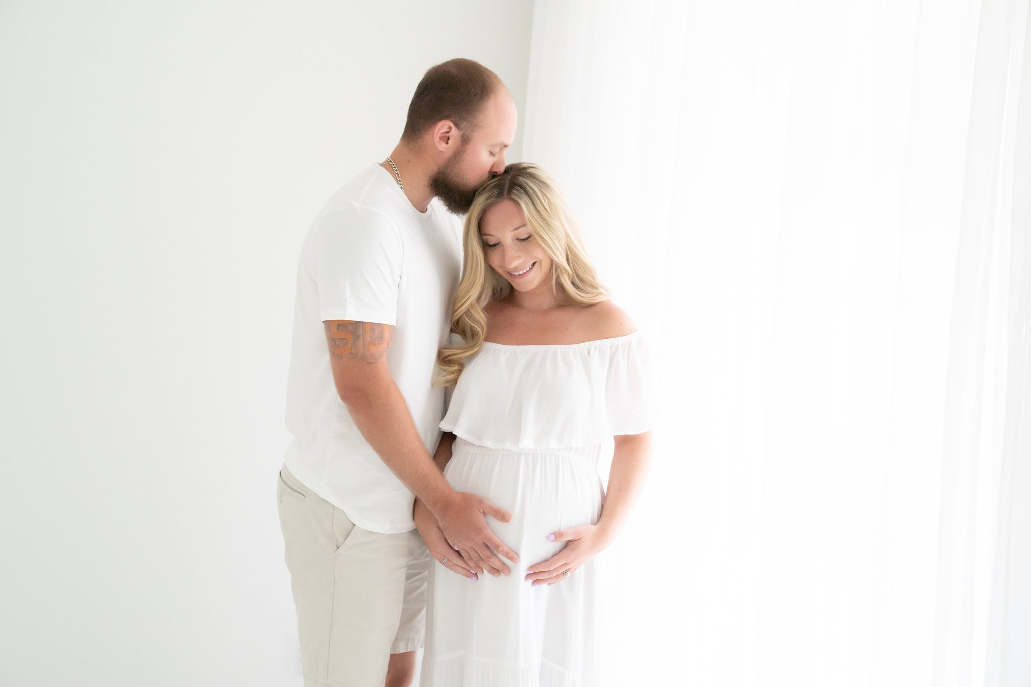 Expected mother with husband wearing a white studio maxi dress in Jupiter Florida photography studio