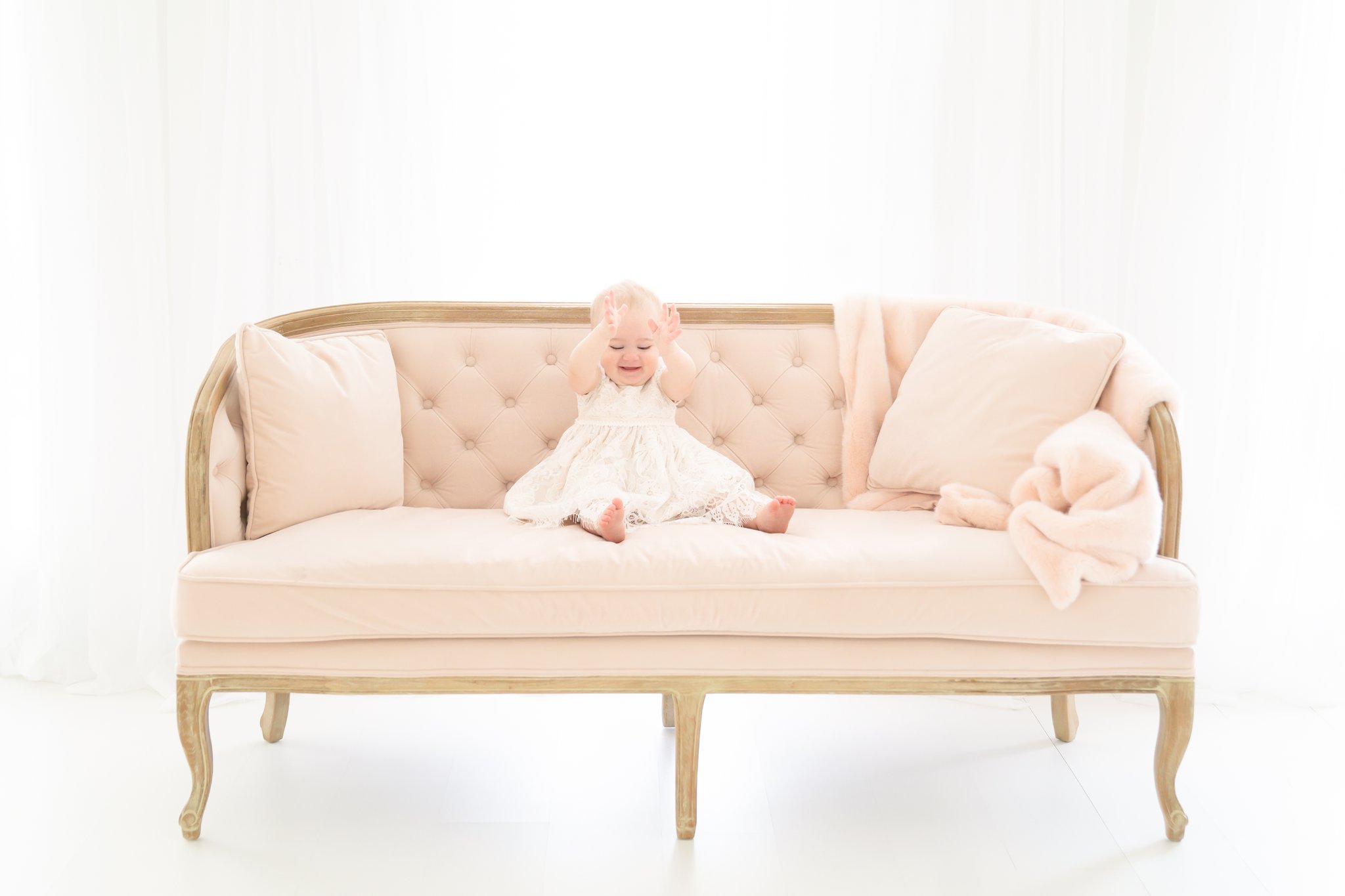 One year old in her christening gown on pink velvet couch