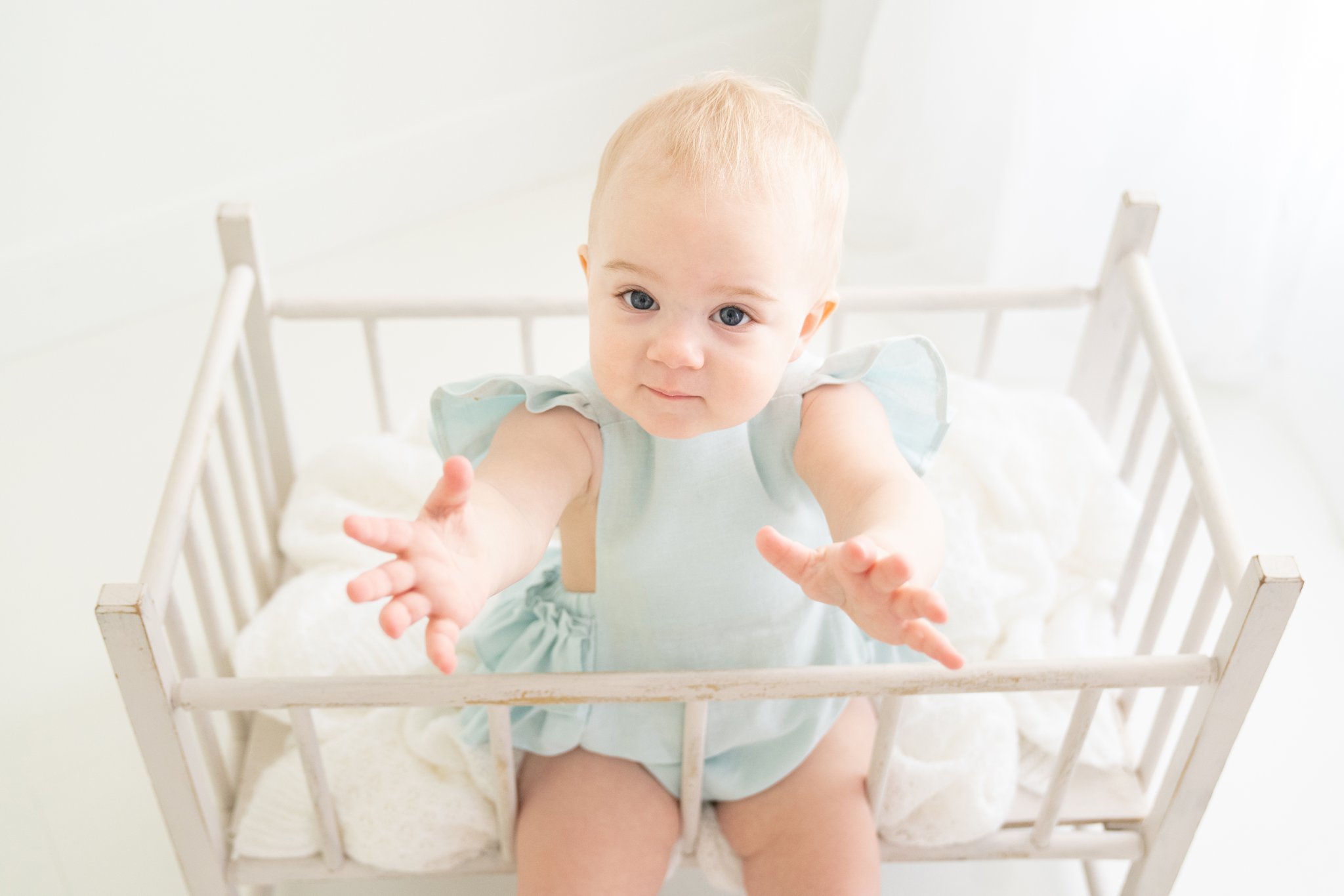 one year old baby in vintage crib with blue handmade romper
