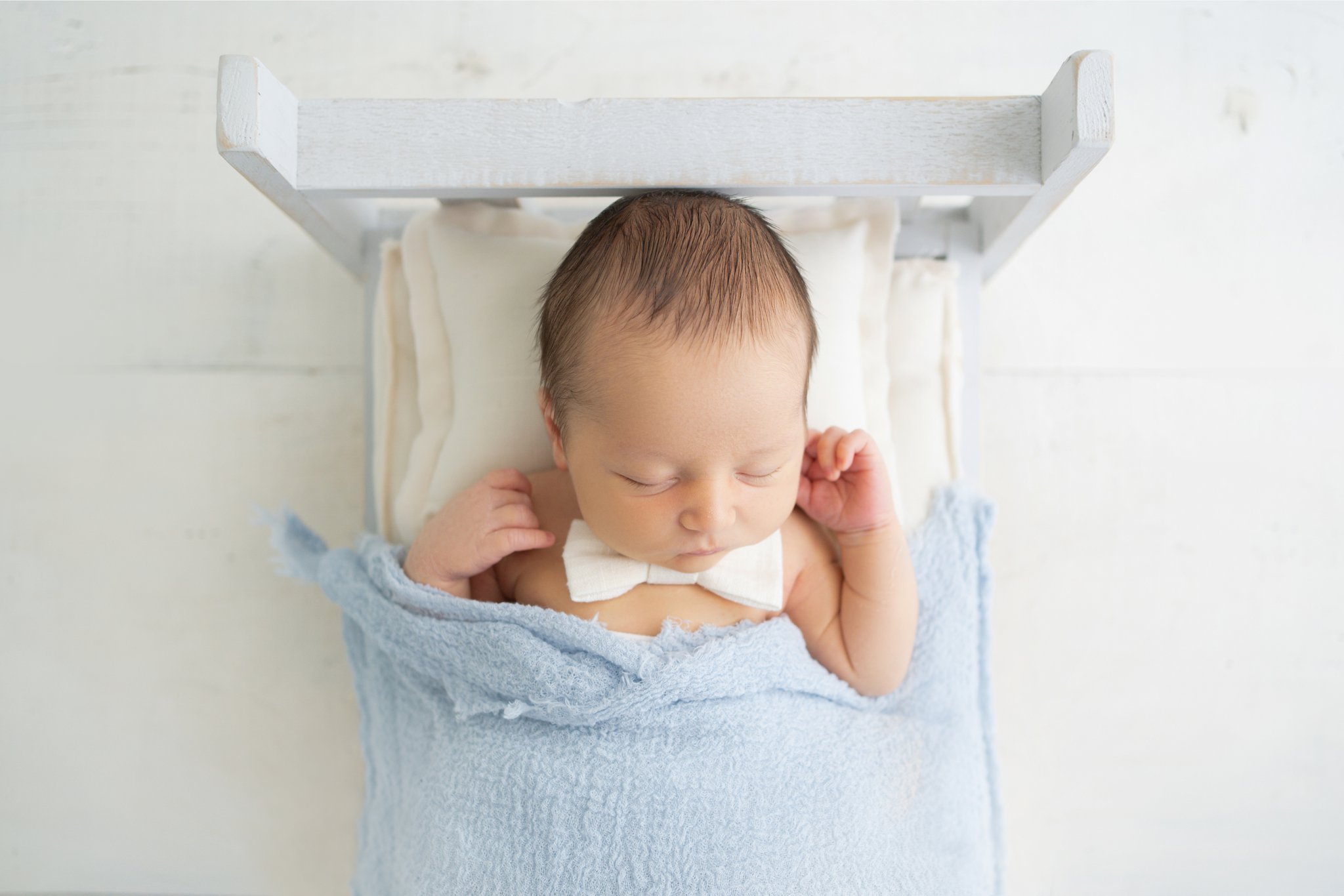 10 day old newborn baby being photographed in Jupiter Florida on a baby bed prop