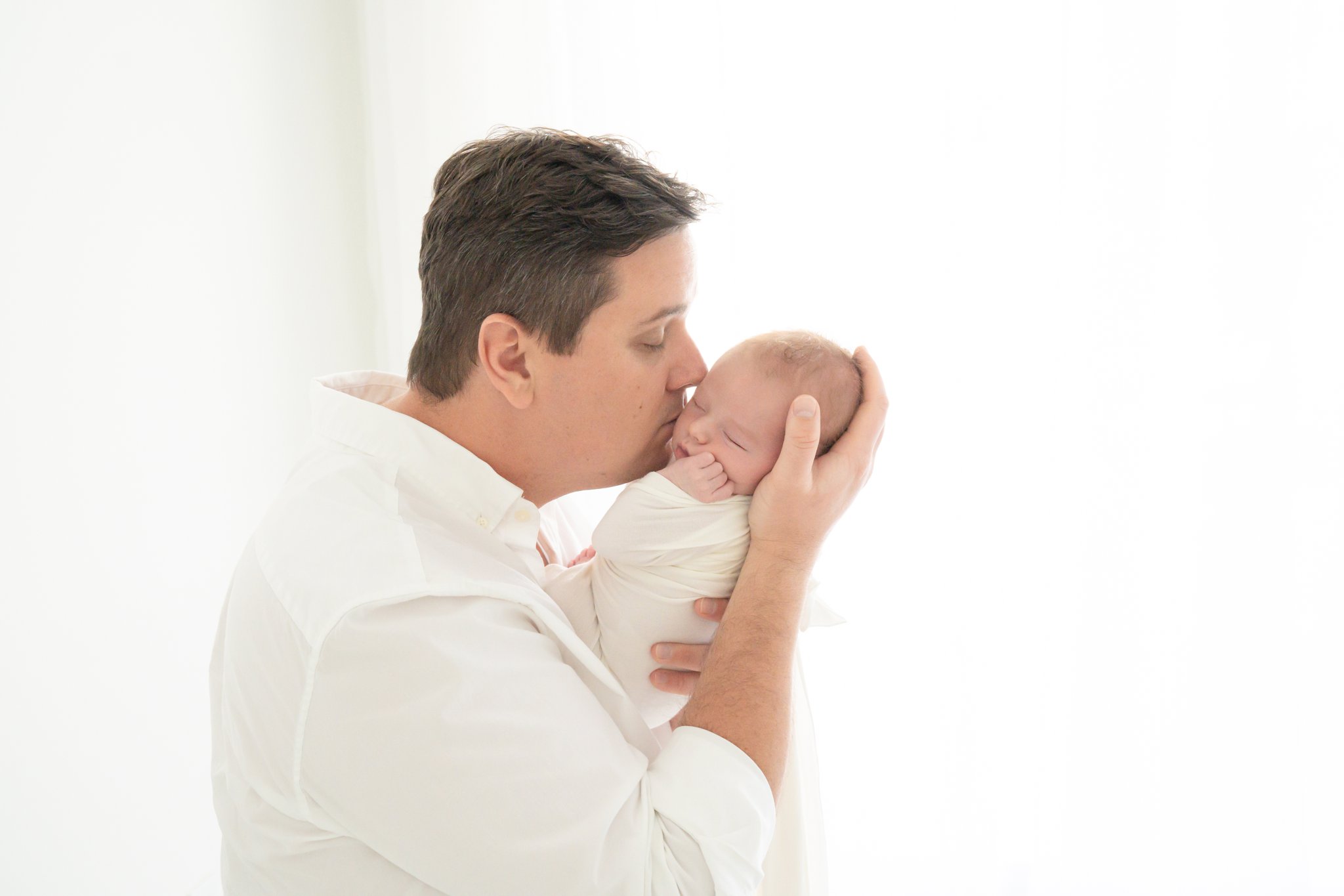 Newborn baby and dad posing for the photographer in studio in Jupiter Fl
