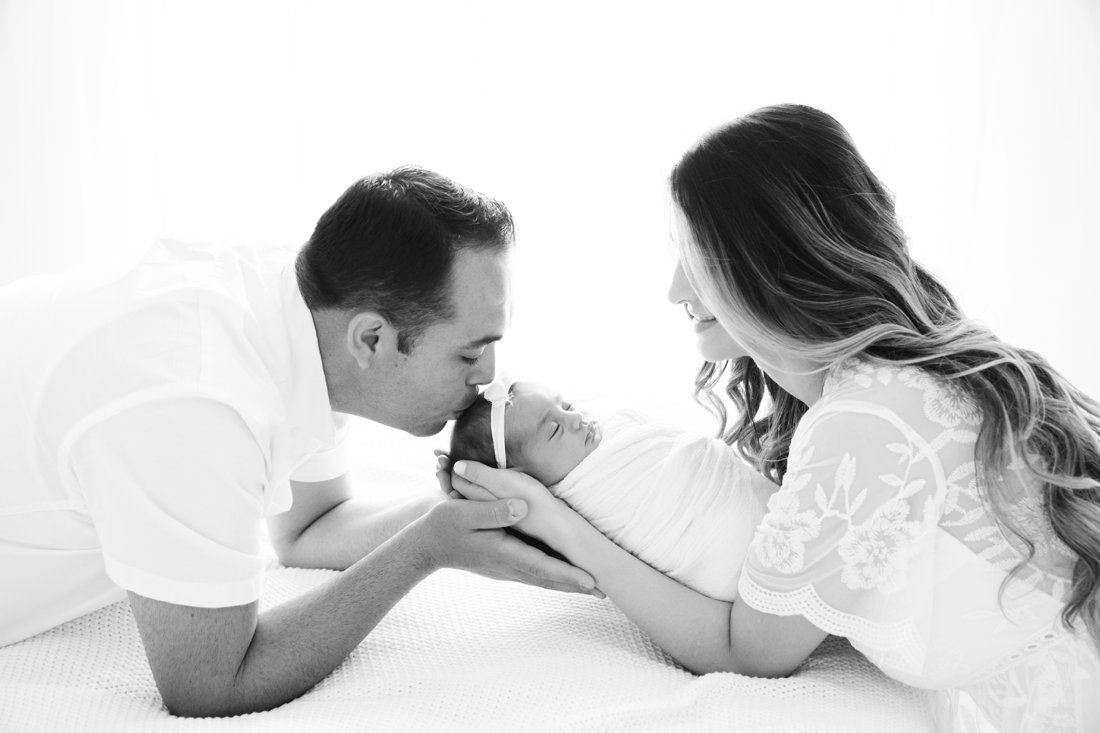 Mom and dad holding their newborn baby girl during a newborn photography session.