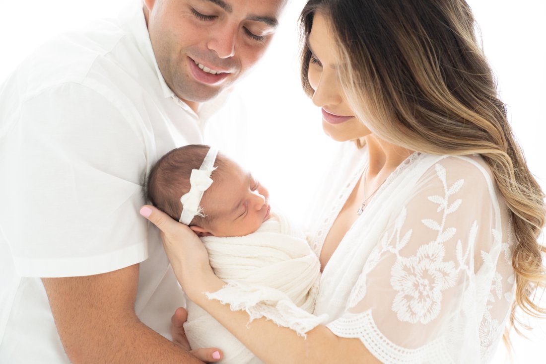 Mom and dad holding their newborn baby girl during a newborn photography session.