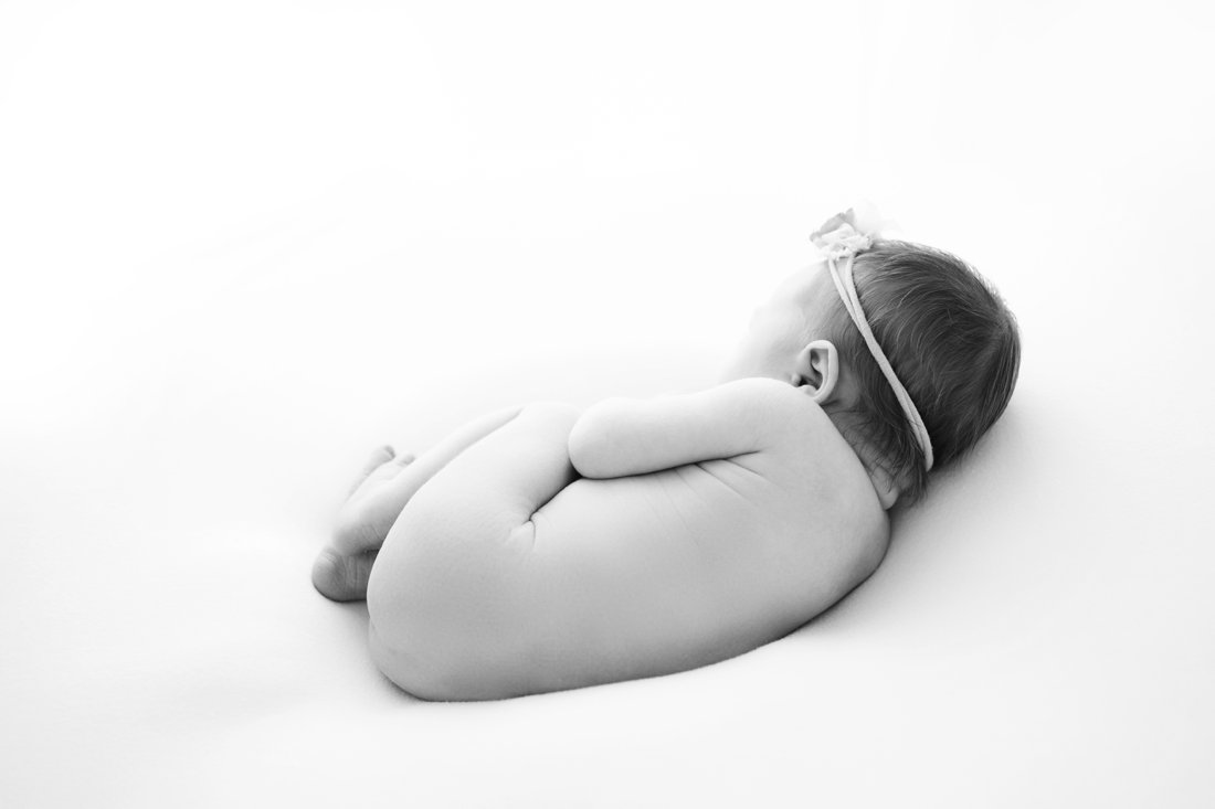 Newborn baby lying on her side with a headband
