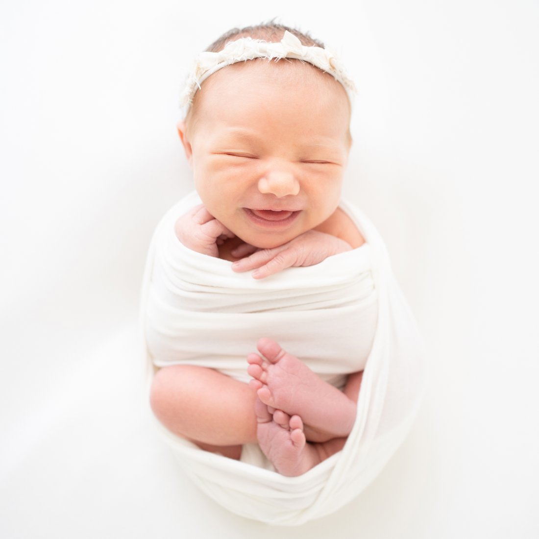 Newborn baby lying on her back with a big smile