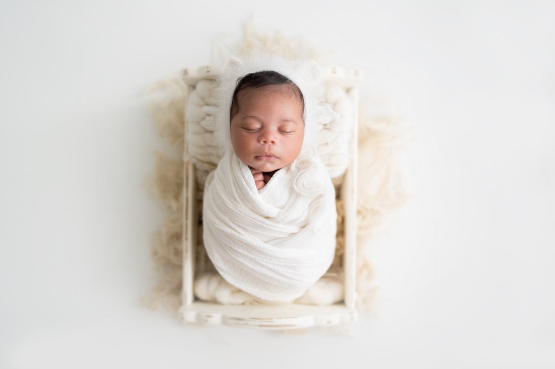 Newborn baby boy lying in a cream cradle