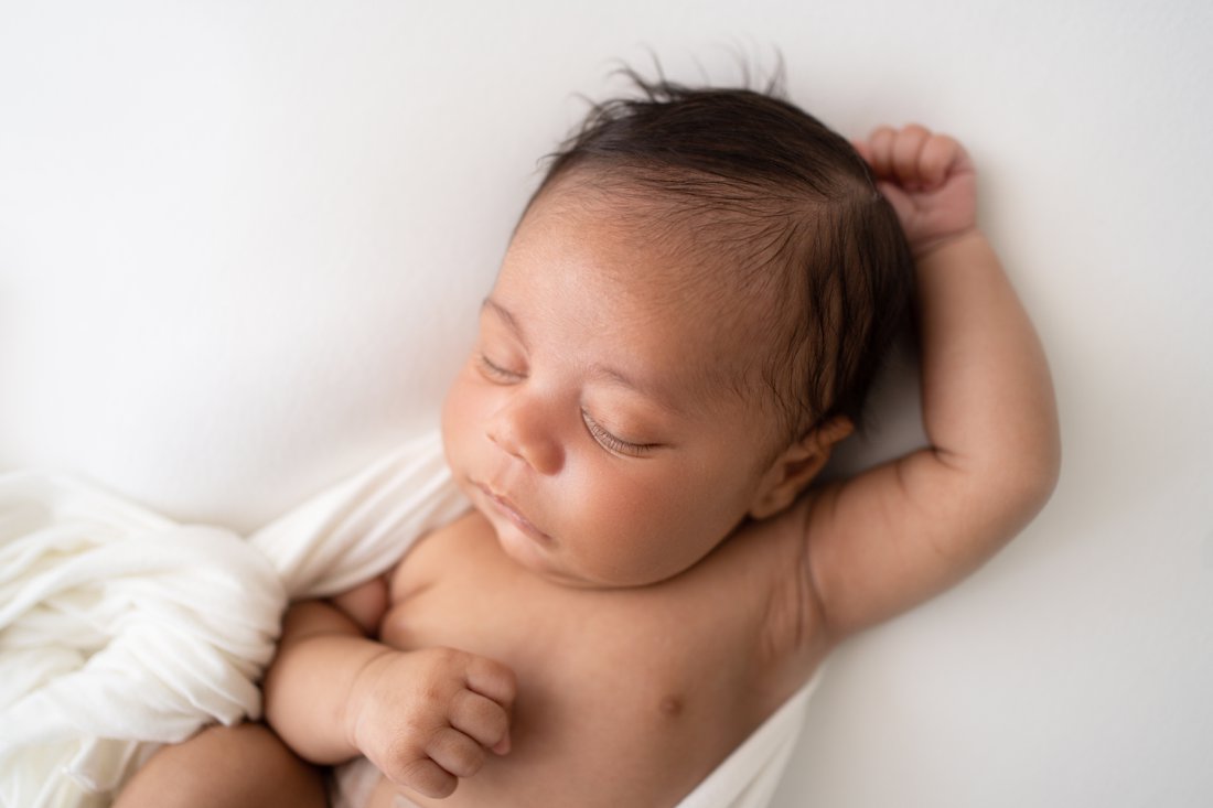 Newborn baby boy lying oin huck finn pose