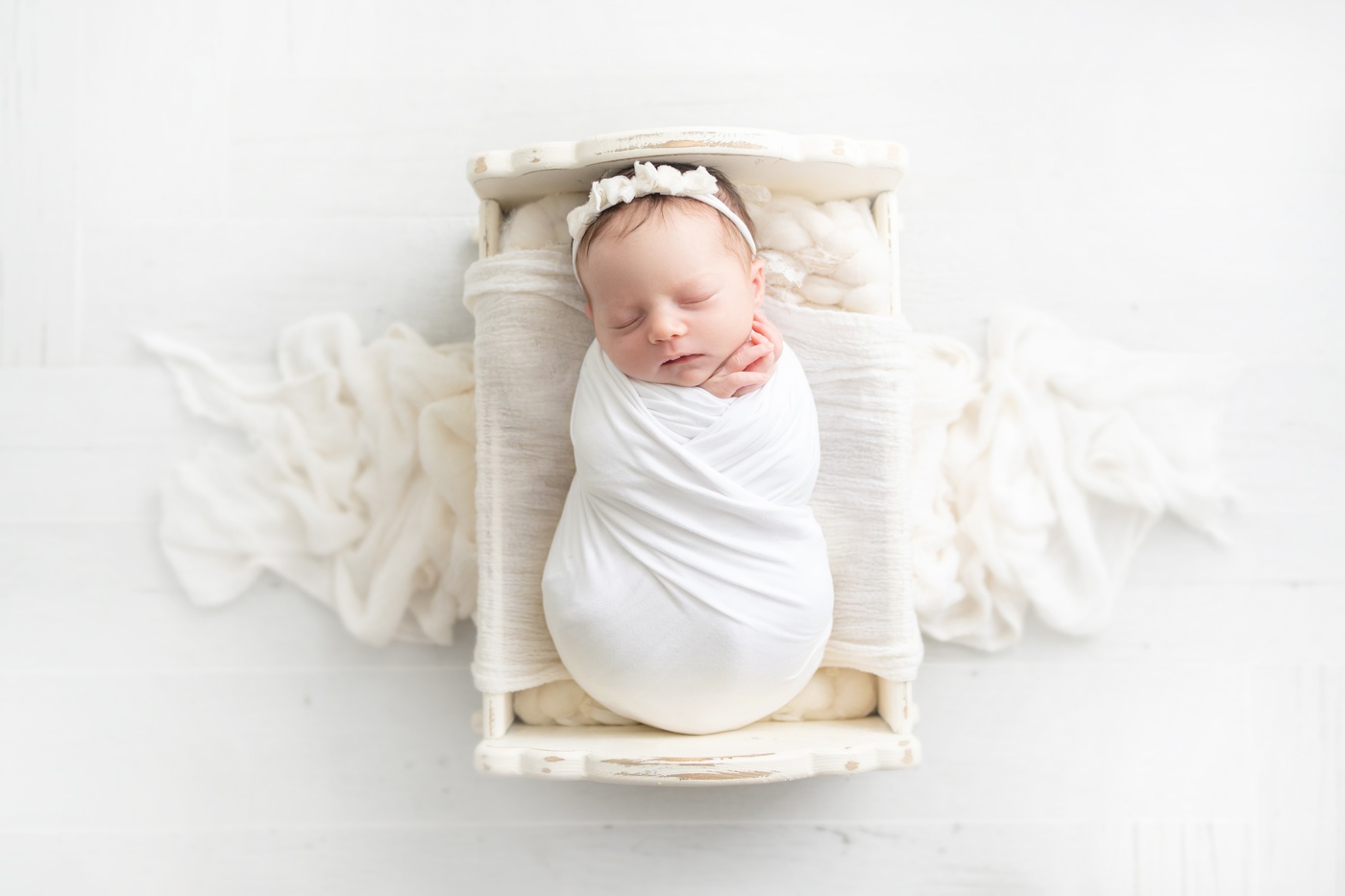  newborn baby in a cream cradle prop