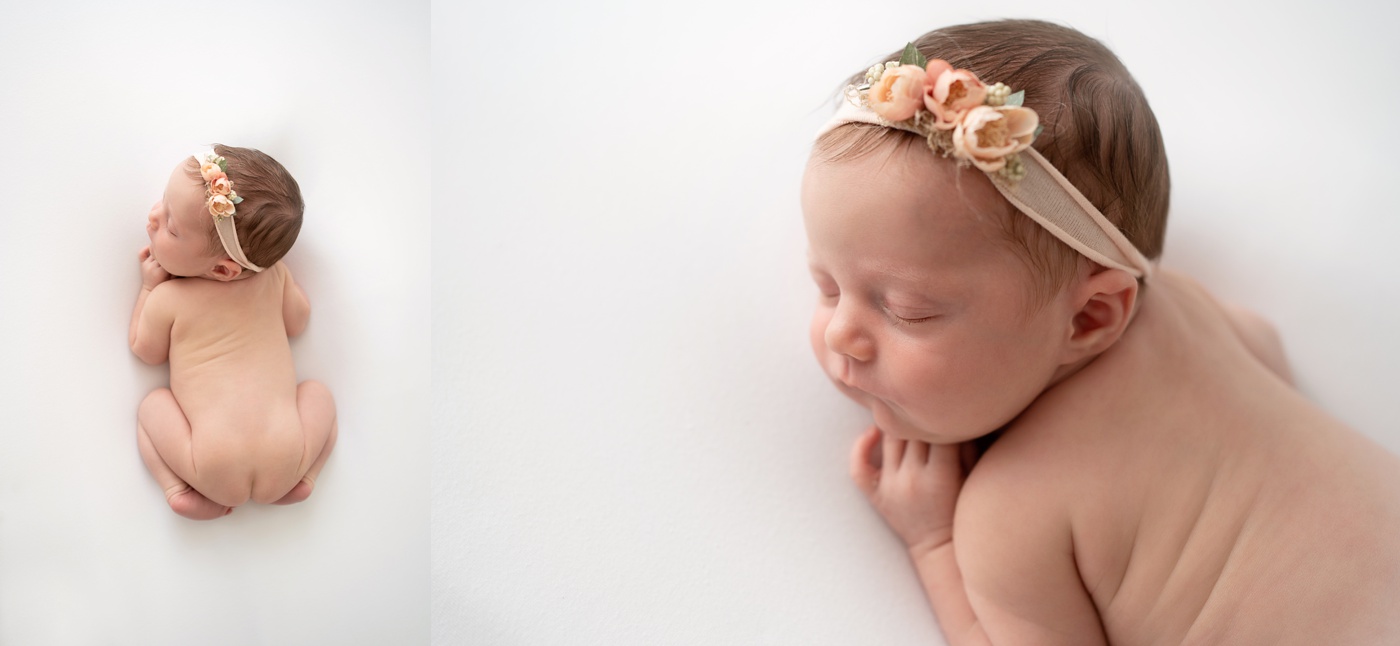  newborn baby girl laying on cream backdrop woith a pink headband sleeping curled up with her hand under her chin