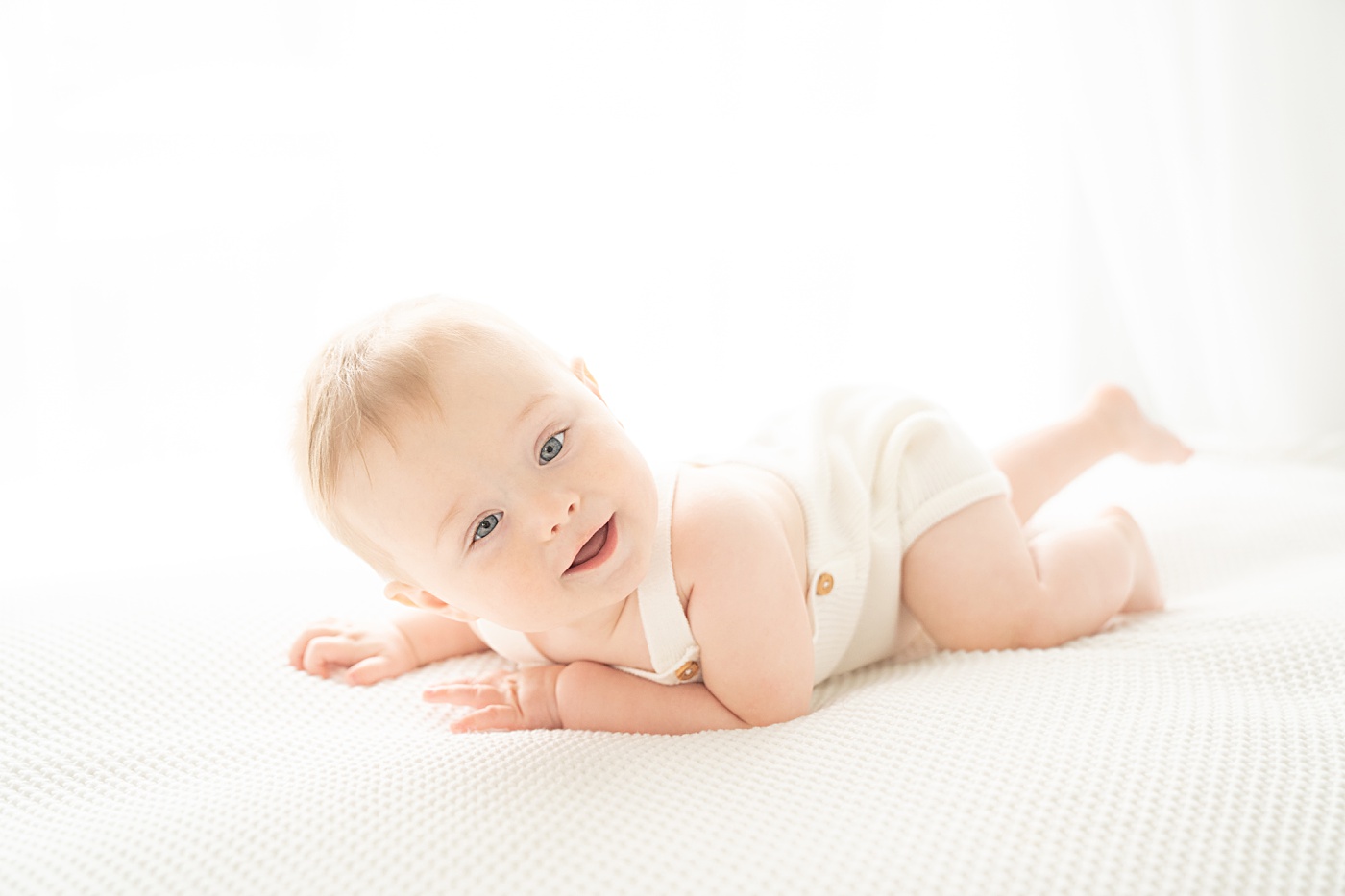 baby boy wearing white overalls being photographed in a jupiter florida photography studio