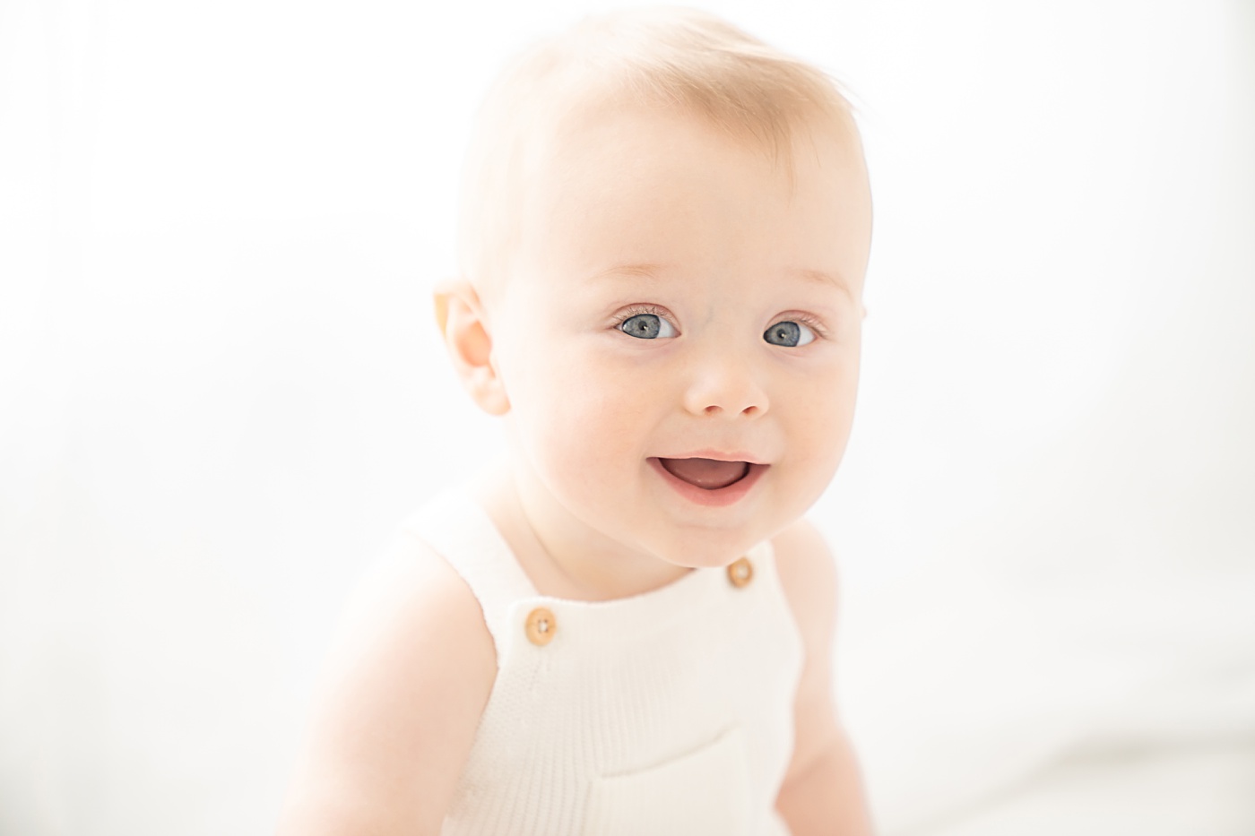 baby boy wearing white overalls being photographed in a jupiter florida photography studio