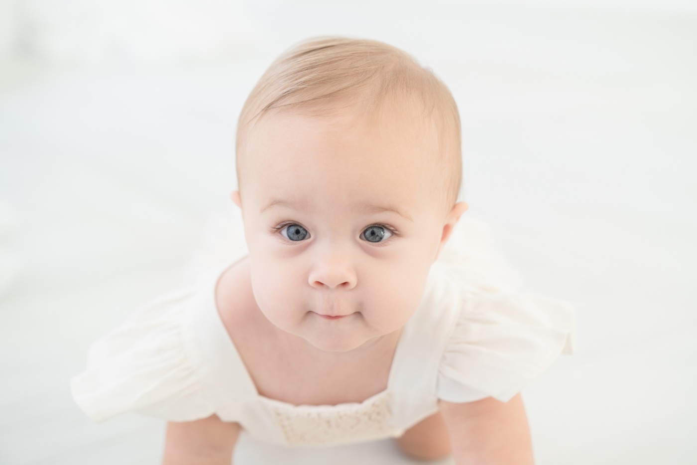 Baby in off white romper in an all white Jupiter Fl photo studio